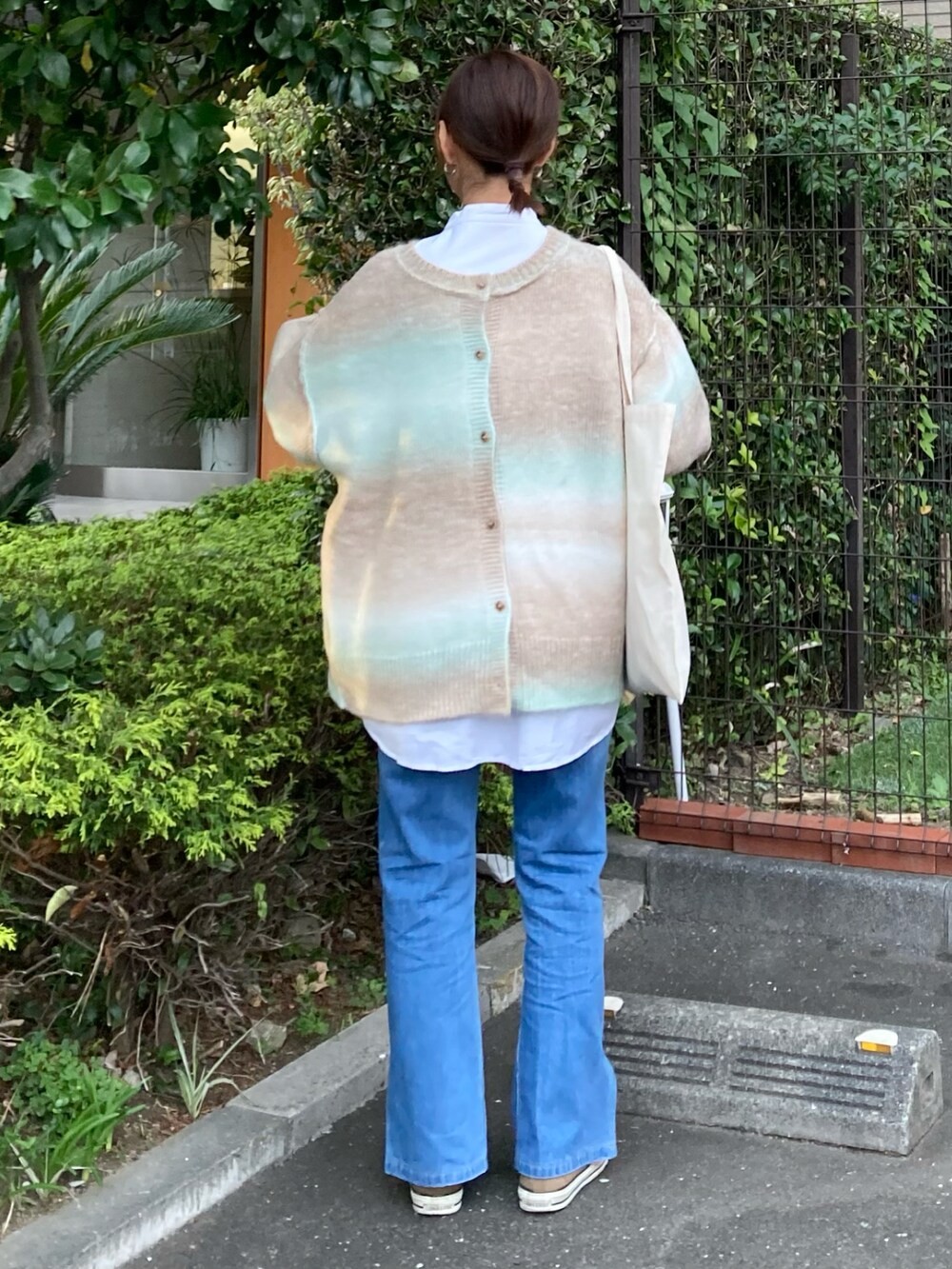 グリーン系のカーディガン/ボレロ、ホワイト系のシャツ/ブラウス、ブルー系のデニムパンツを着用したレディースの秋コーディネートの5枚目の写真