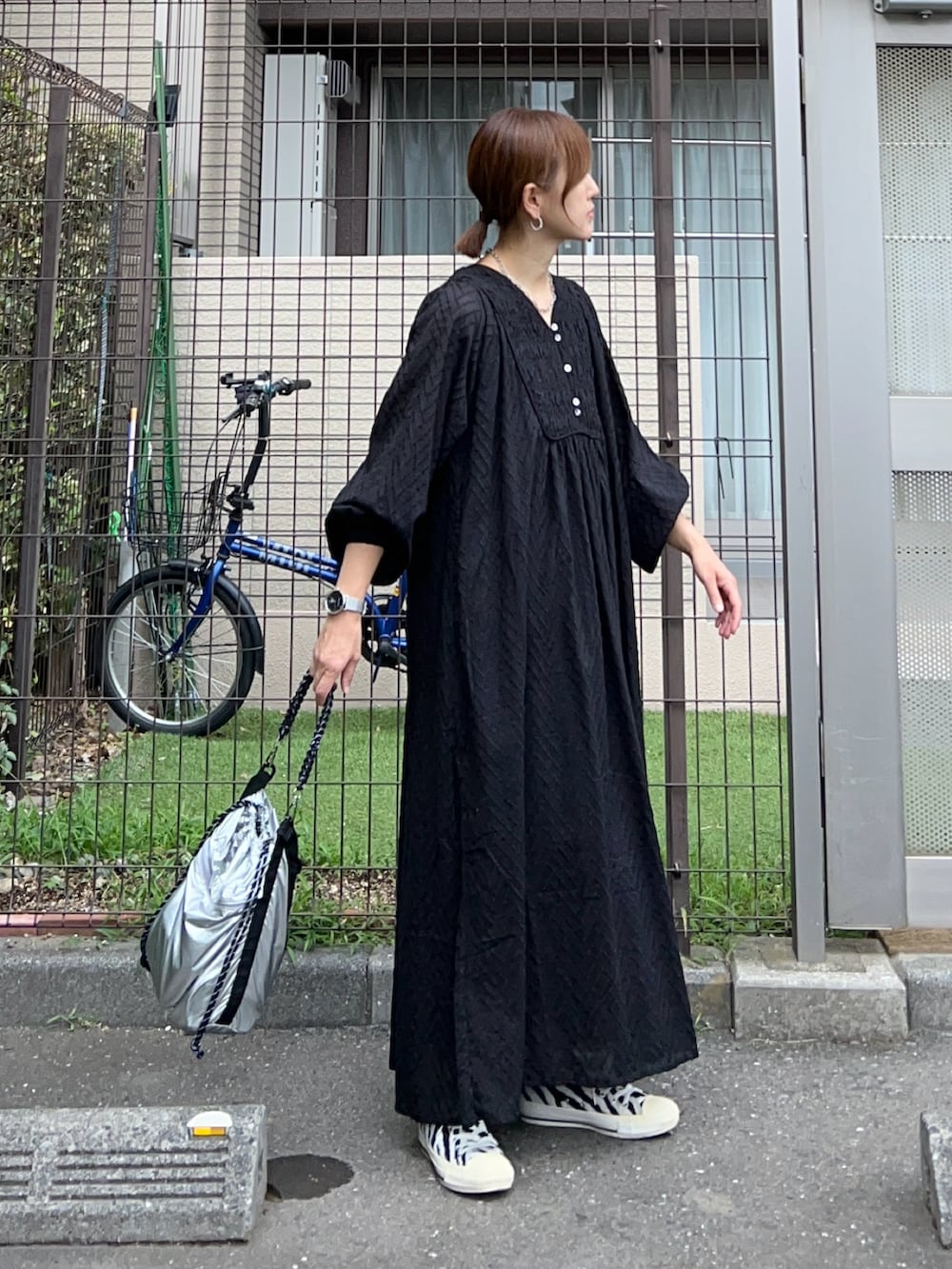 ブラック系のワンピース、シルバー系のトートバッグ、ホワイト系のスニーカーを着用したレディースの夏コーディネートの2枚目の写真