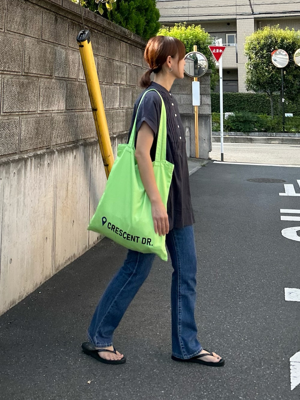 ブルー系のデニムパンツ、グレー系のシャツ/ブラウス、グリーン系のトートバッグを着用したレディースの夏コーディネートの4枚目の写真