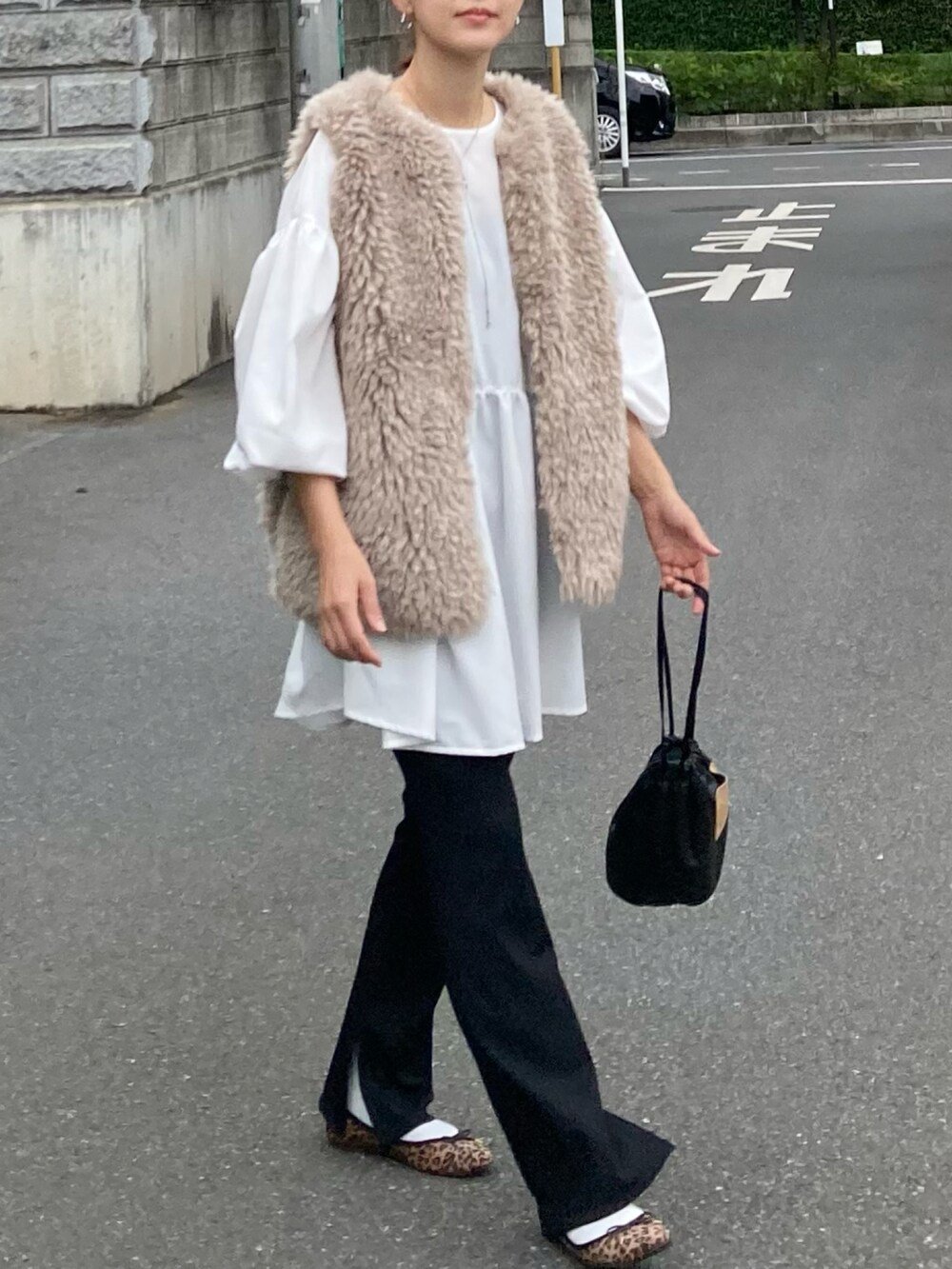 ベージュ系のベスト、ホワイト系のシャツ/ブラウス、ブラック系のハンドバッグを着用したレディースの秋コーディネートの3枚目の写真