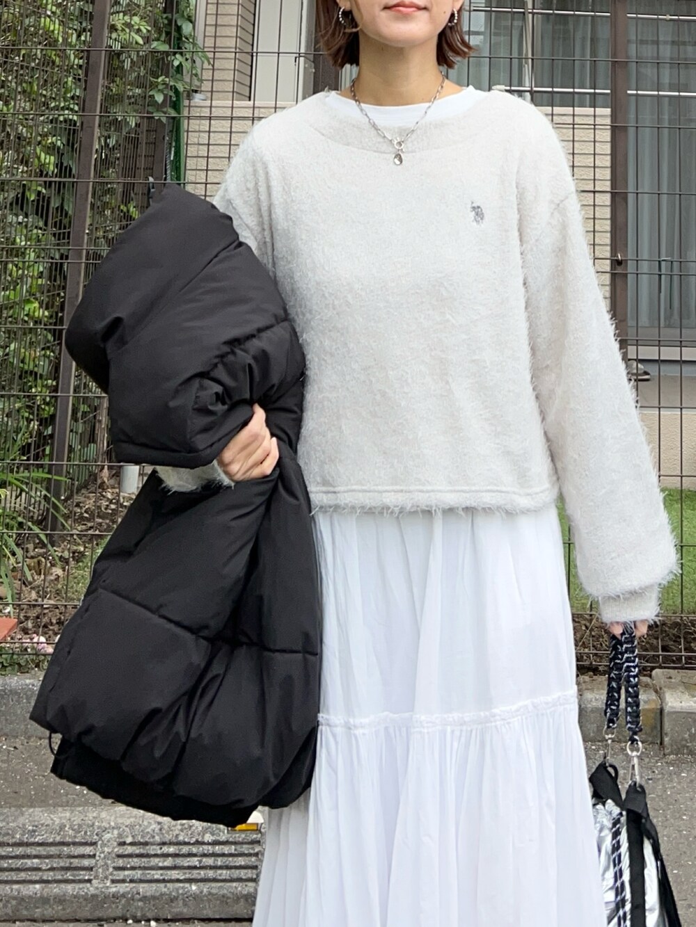 グレー系のニット/セーター、ホワイト系のスカート、シルバー系のショルダーバッグを着用したレディースの秋コーディネートの4枚目の写真
