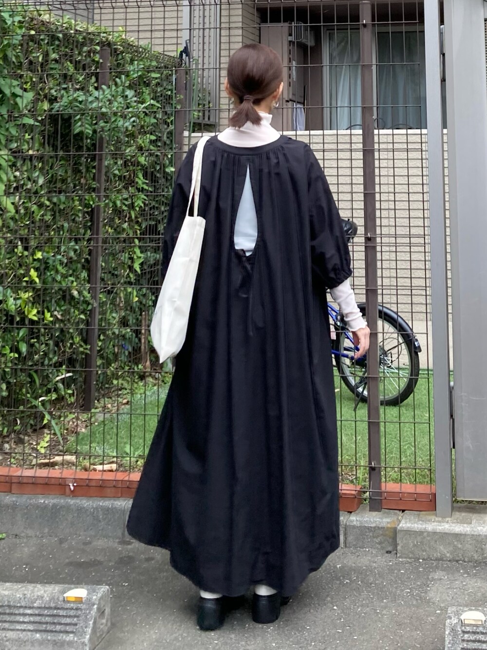 ブラック系のワンピース、ホワイト系のトートバッグ、ホワイト系のブーツを着用したレディースの秋コーディネートの2枚目の写真