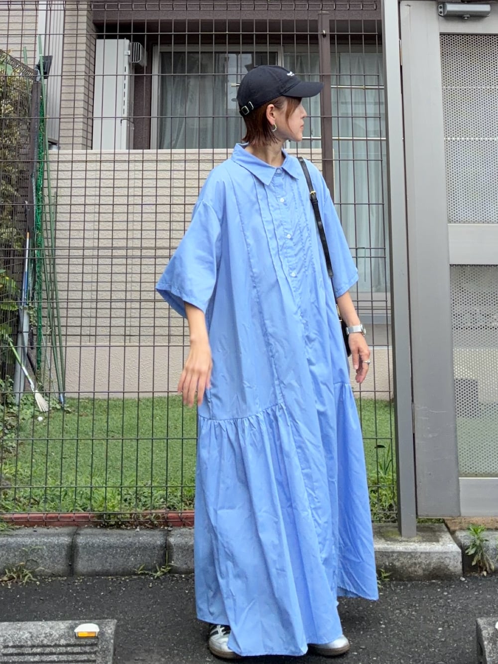 ブルー系のシャツワンピース、ブラック系のキャップ、ブラック系の財布を着用したレディースの夏コーディネートの2枚目の写真
