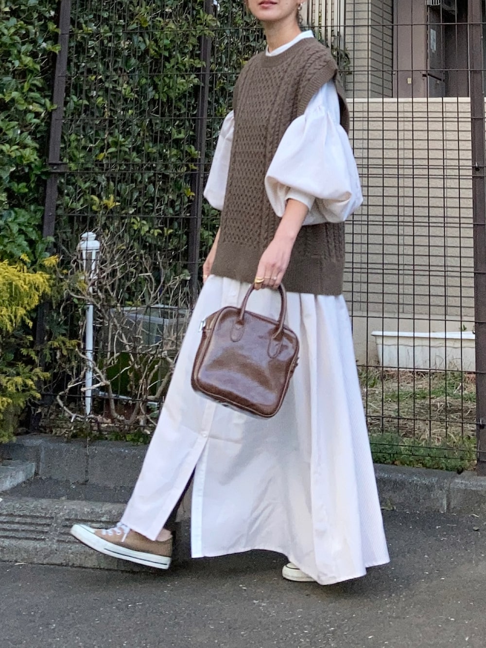 ブラウン系のベスト、ベージュ系のワンピース、ブラウン系のショルダーバッグを着用したレディースの冬コーディネートの4枚目の写真