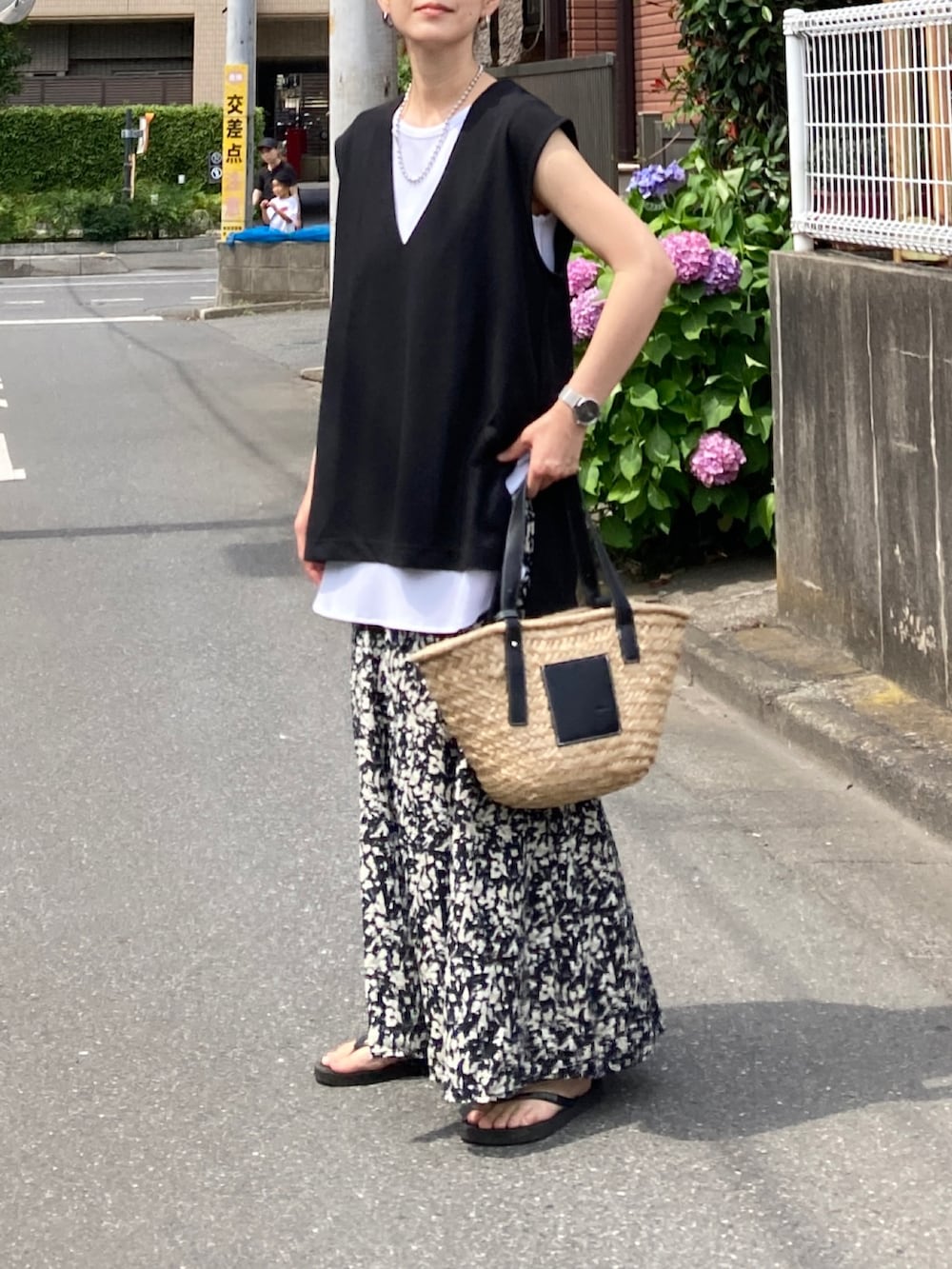 ブラック系のベスト、ブラック系のスカート、ブラック系のかごバッグを着用したレディースの夏コーディネートの2枚目の写真