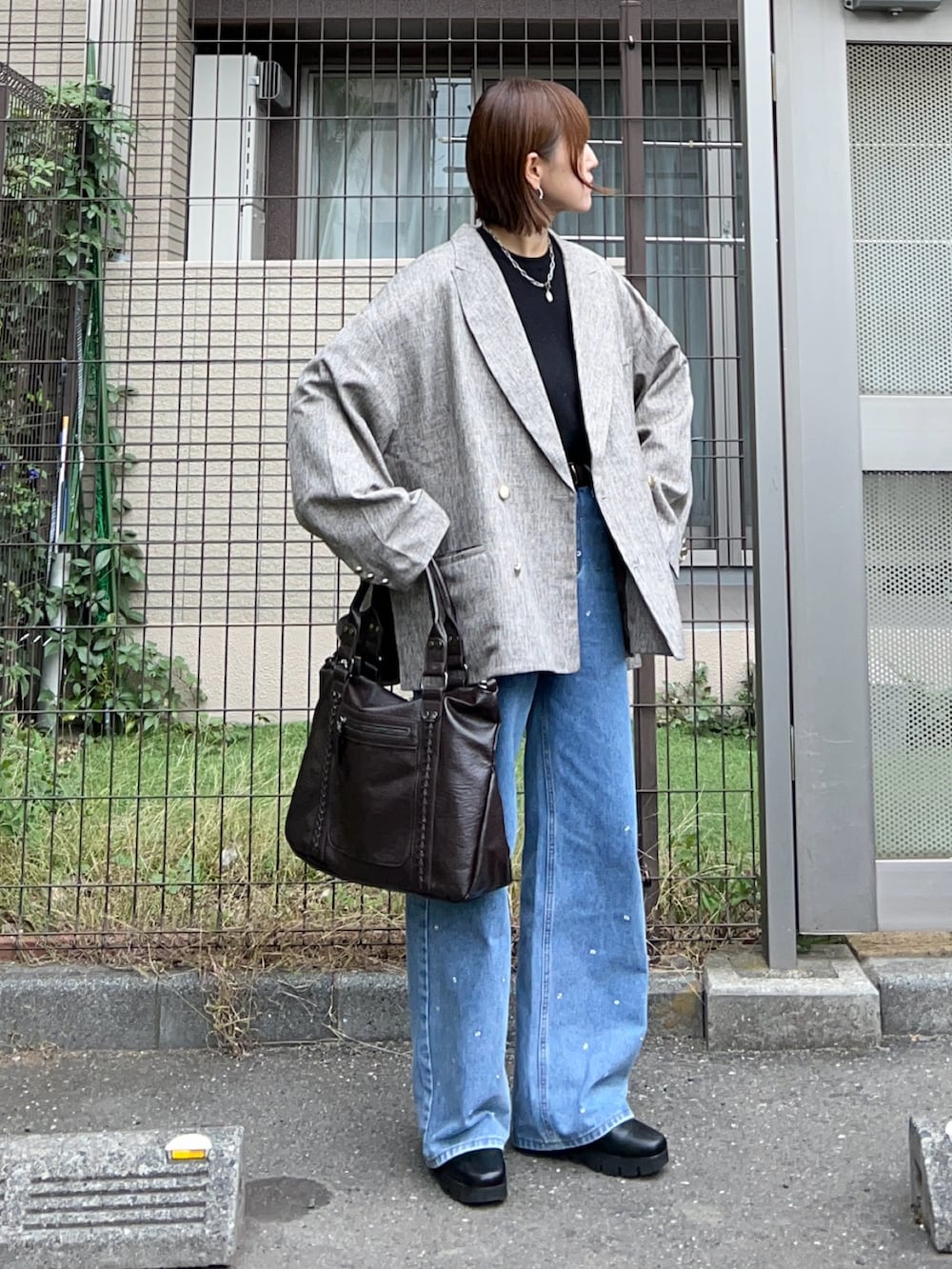 ベージュ系のテーラードジャケット、ブラウン系のトートバッグ、ブラック系のニット/セーターを着用したレディースの秋コーディネートの3枚目の写真