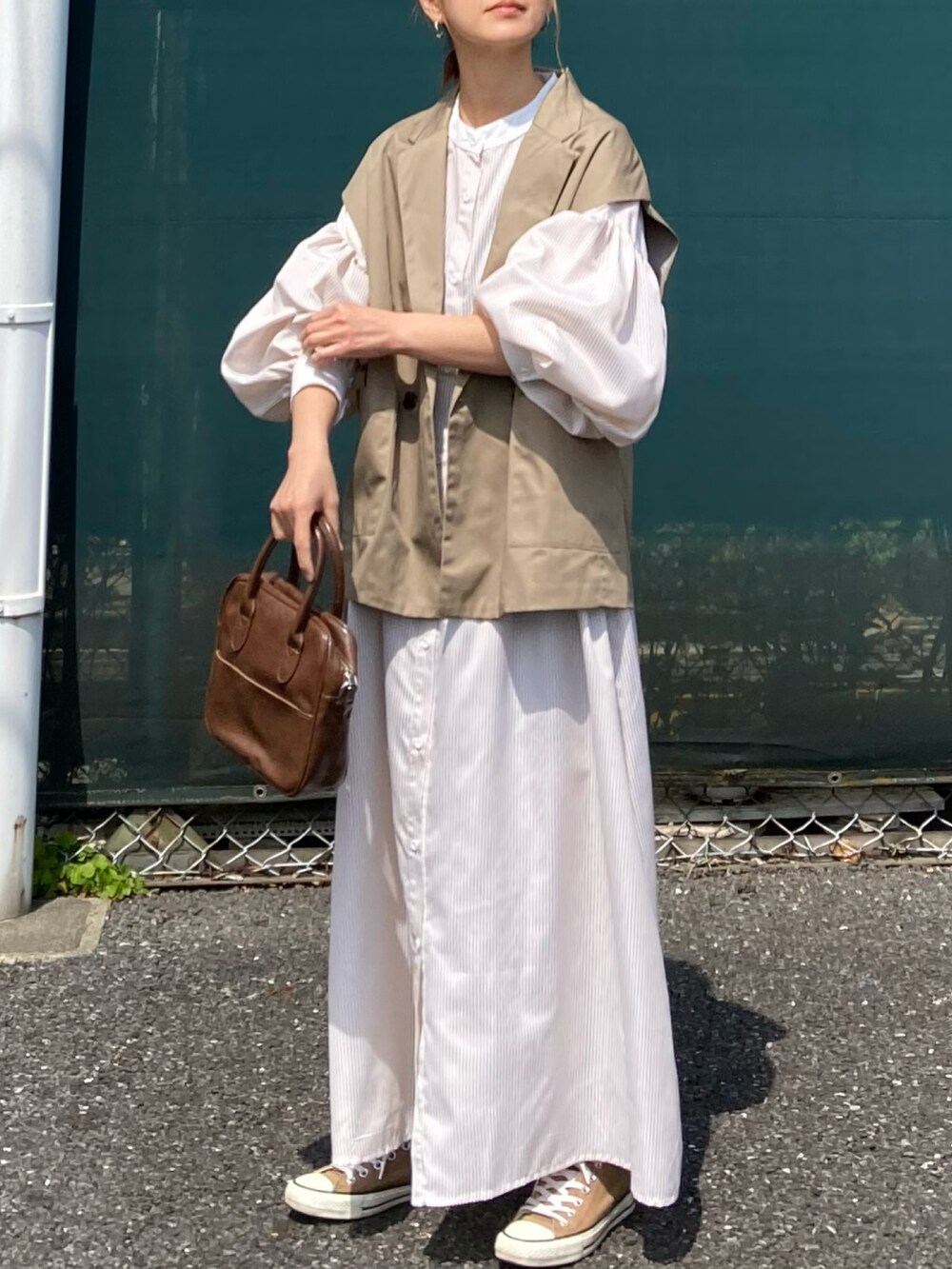 ベージュ系のベスト、ベージュ系のワンピース、ブラウン系のショルダーバッグを着用したレディースの春コーディネートの4枚目の写真