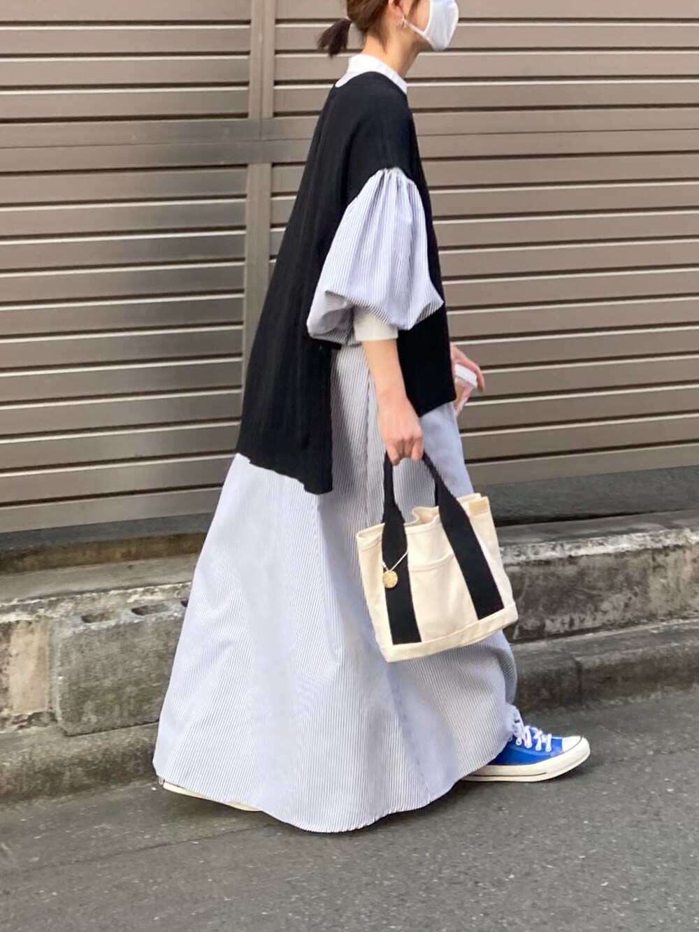 ブラック系のワンピース、ブラック系のベスト、ホワイト系のトートバッグを着用したレディースの春コーディネートの4枚目の写真