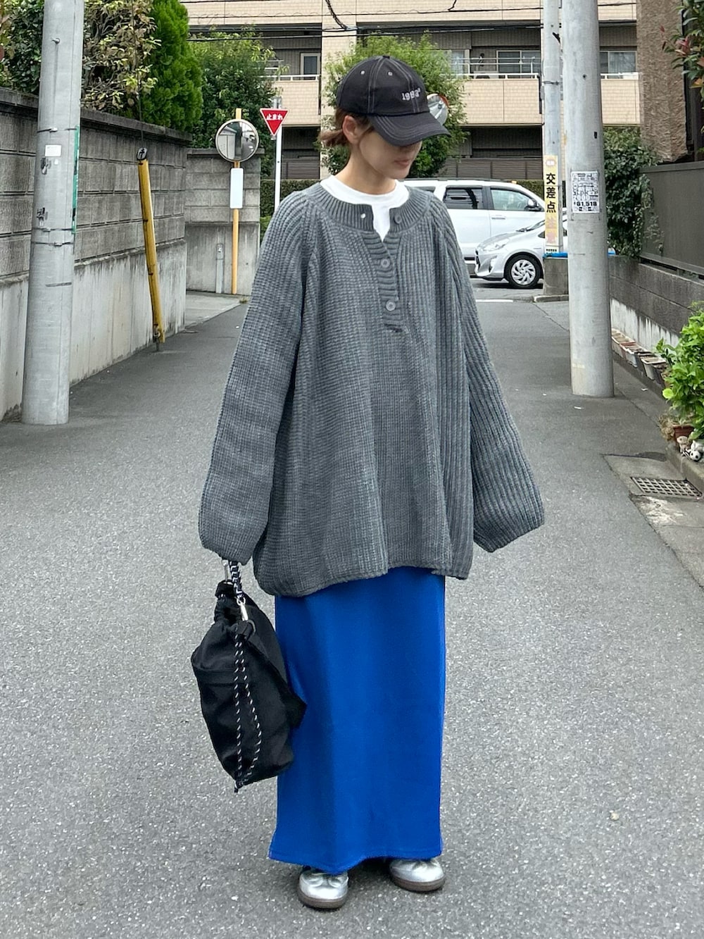 グレー系のニット/セーター、ブラック系のショルダーバッグ、ブルー系のスカートを着用したレディースの秋コーディネートの4枚目の写真