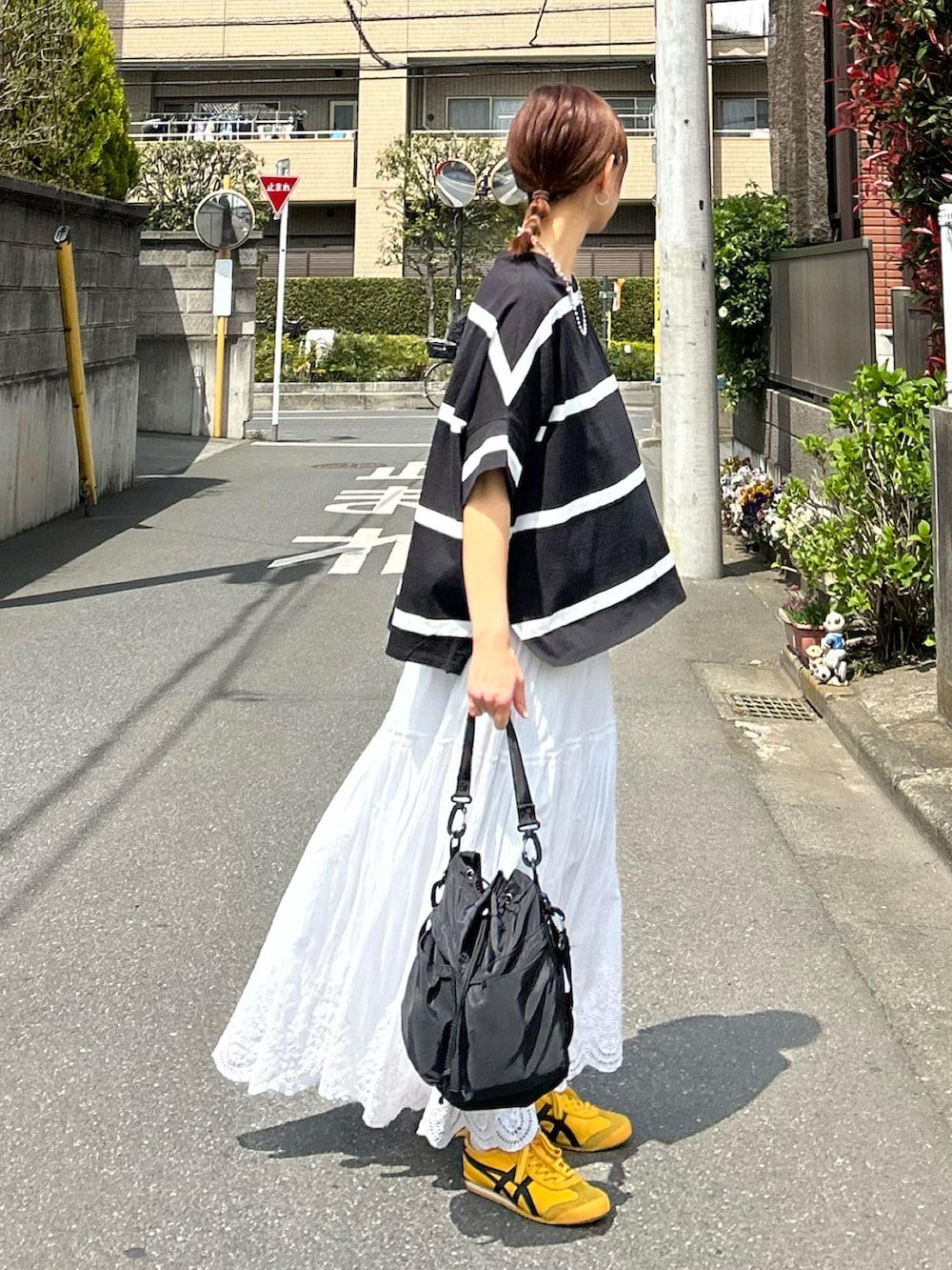 ブラック系のTシャツ/カットソー、ホワイト系のスカート、ブラック系のショルダーバッグを着用したレディースの春コーディネートの3枚目の写真