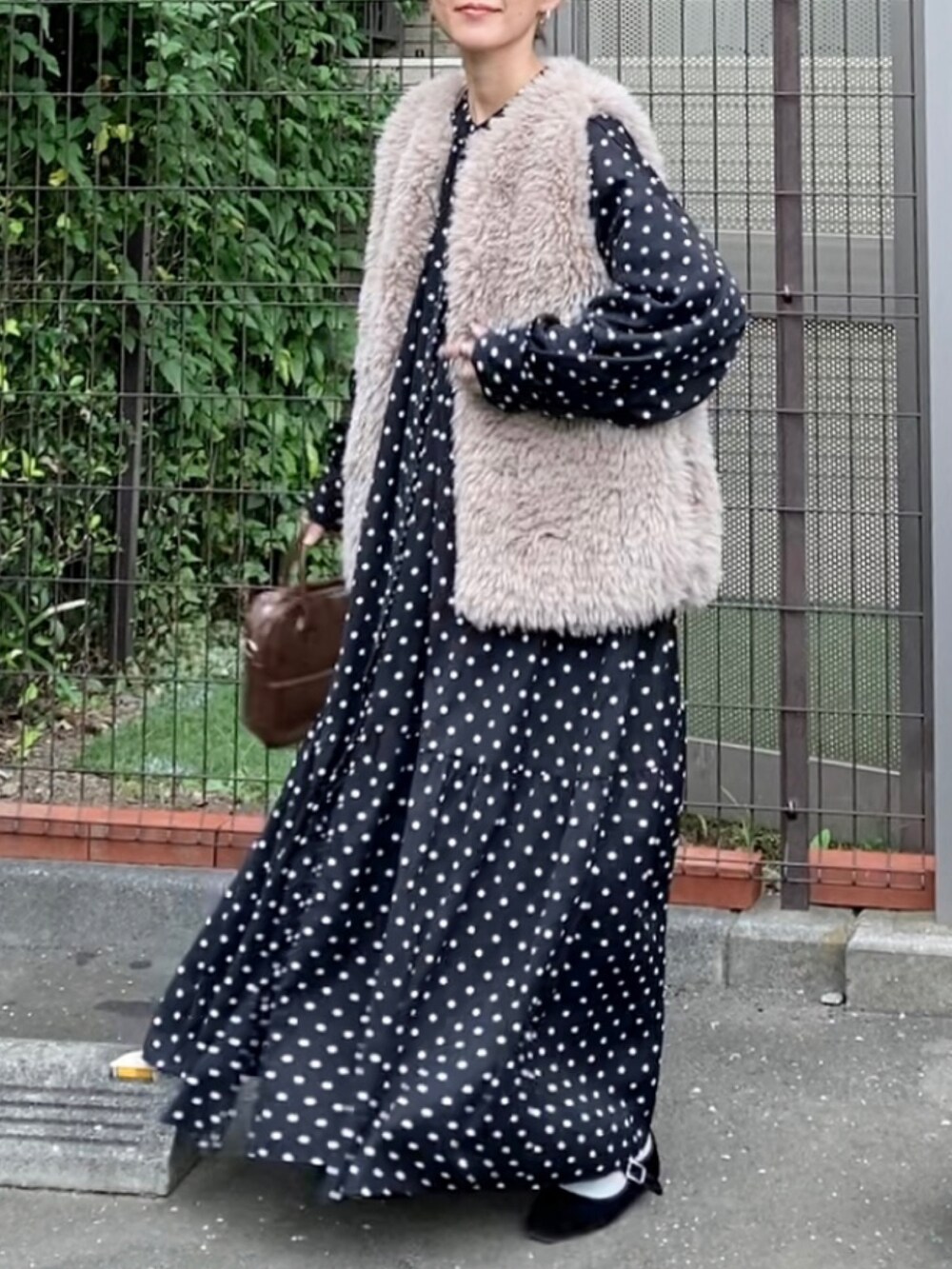 ベージュ系のベスト、ブラック系のシャツワンピース、ブラウン系のショルダーバッグを着用したレディースの秋コーディネートの3枚目の写真