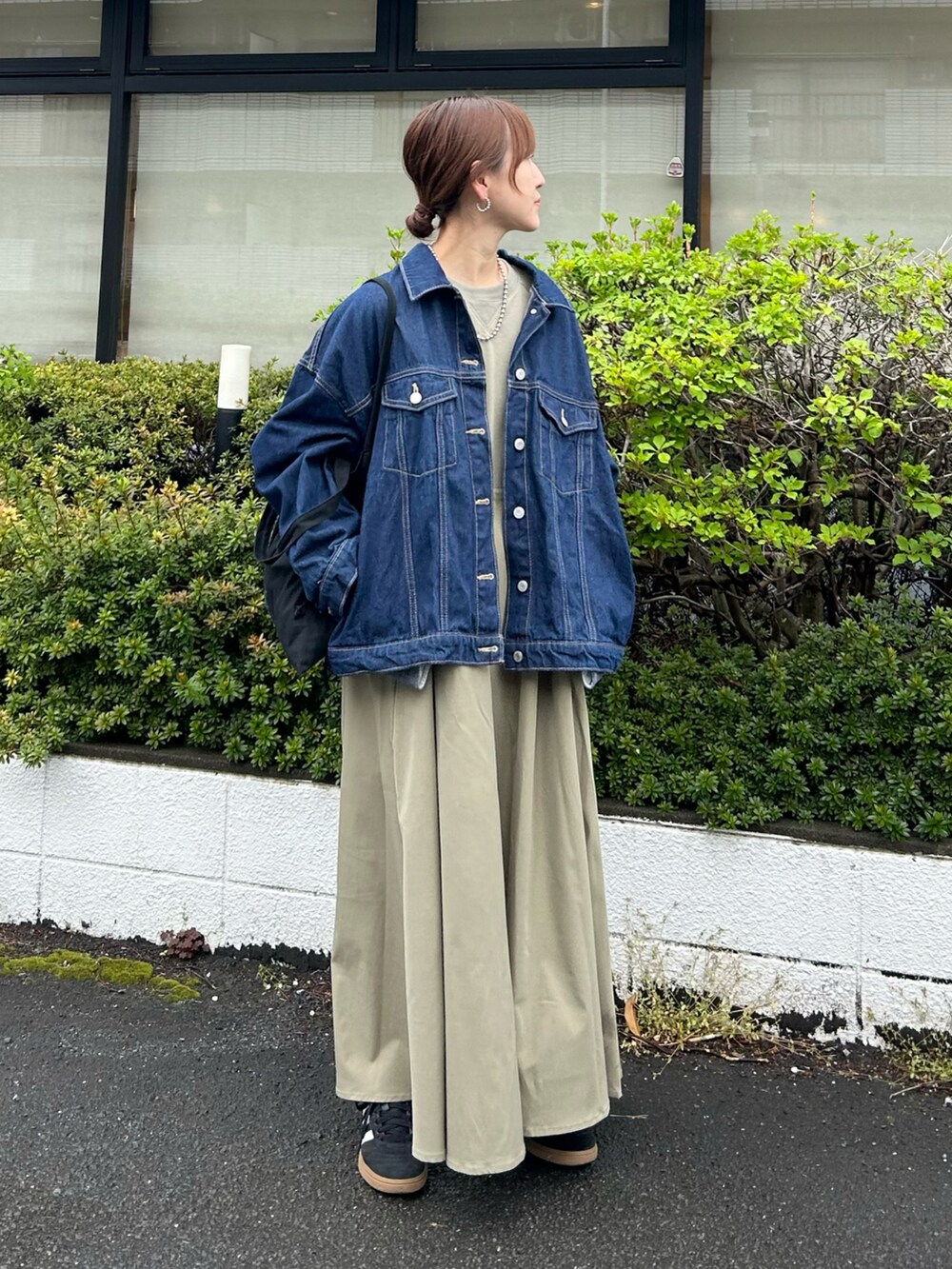 グリーン系のワンピース、ブラック系のトートバッグ、ブルー系のデニムジャケットを着用したレディースの春コーディネートの3枚目の写真