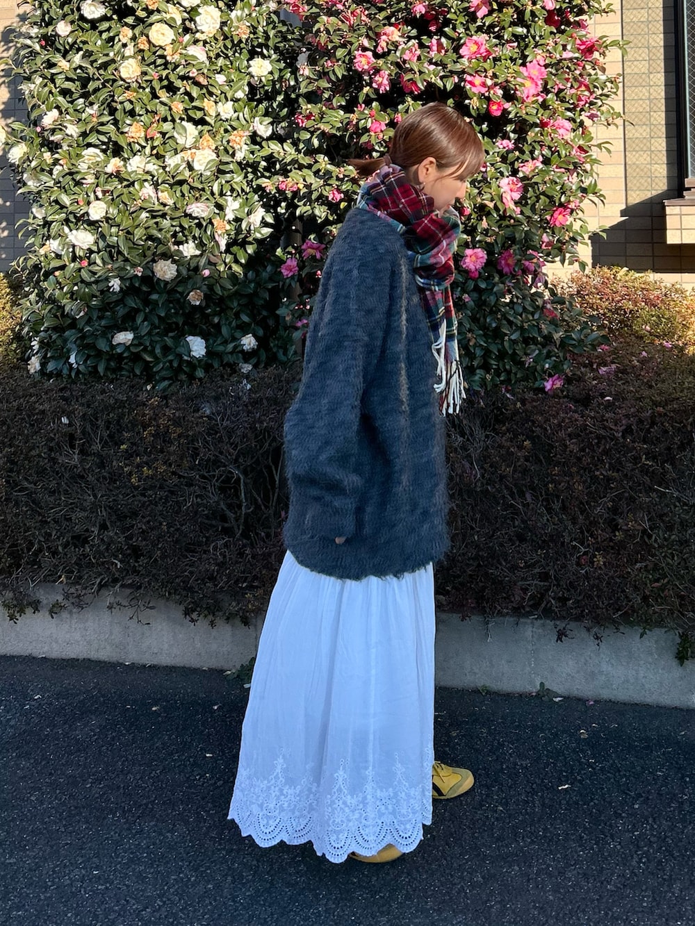 グレー系のTシャツ/カットソー、ホワイト系のスカート、グレー系のカーディガン/ボレロを着用したレディースの冬コーディネートの2枚目の写真