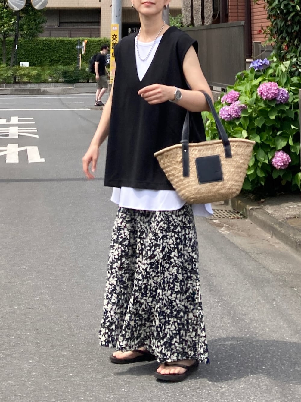 ブラック系のベスト、ブラック系のスカート、ブラック系のかごバッグを着用したレディースの夏コーディネートの3枚目の写真