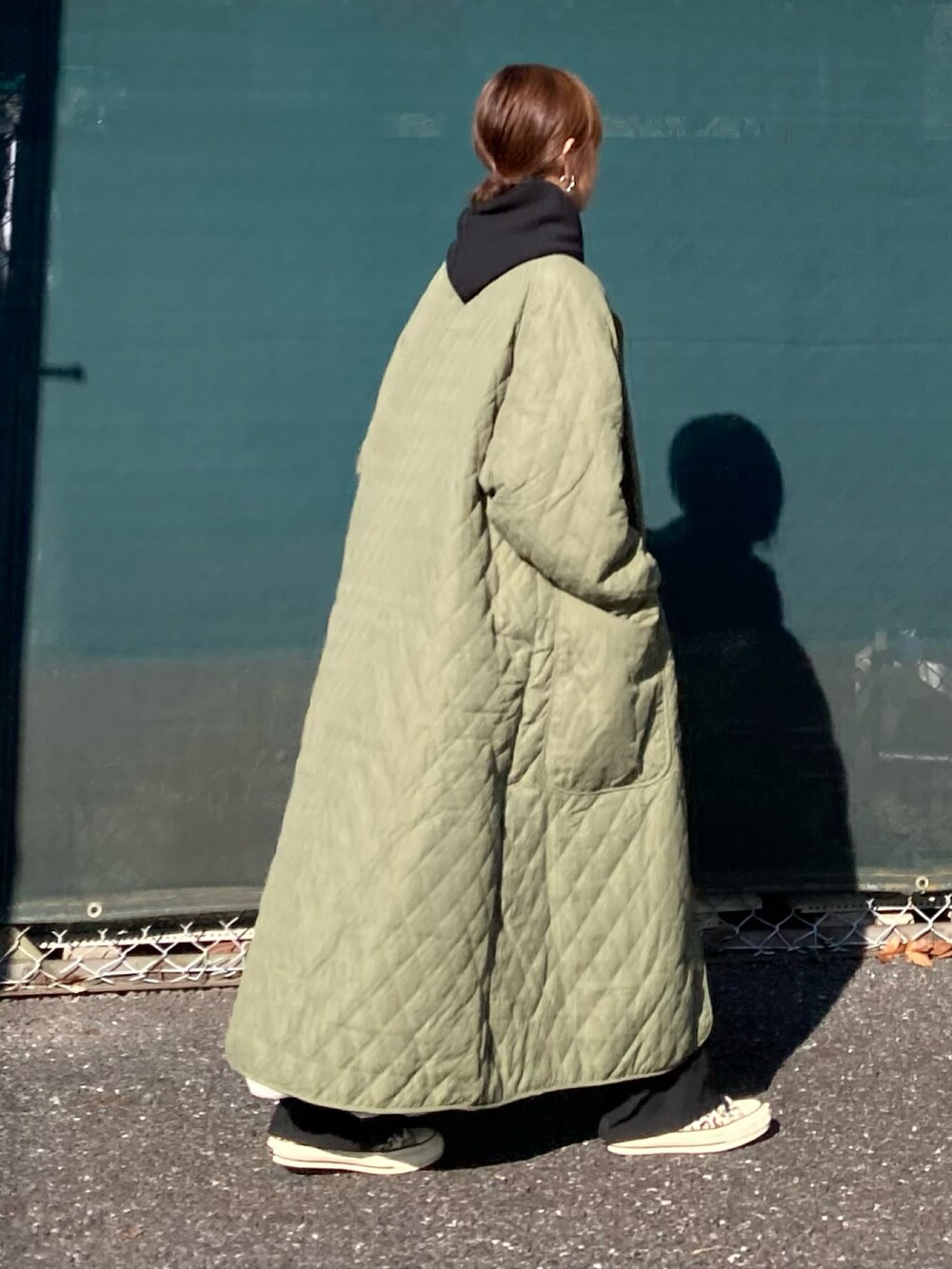 グリーン系のダウンジャケット/コート、ブラック系のパーカー、ブラック系のその他パンツを着用したレディースの冬コーディネートの4枚目の写真