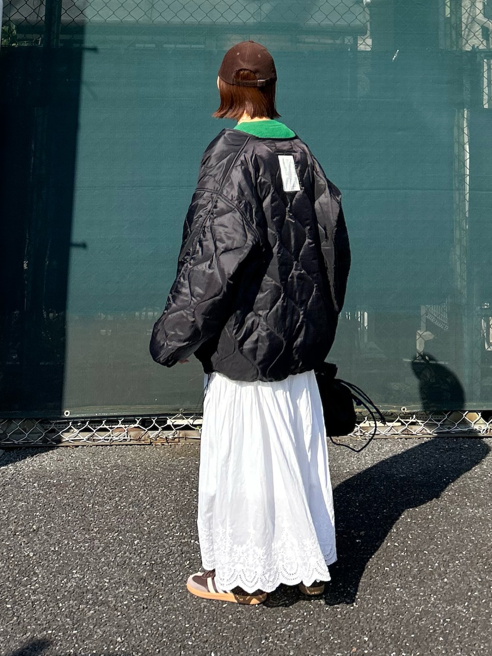 ブラック系のブルゾン、グリーン系のニット/セーター、ホワイト系のスカートを着用したレディースの冬コーディネートの5枚目の写真