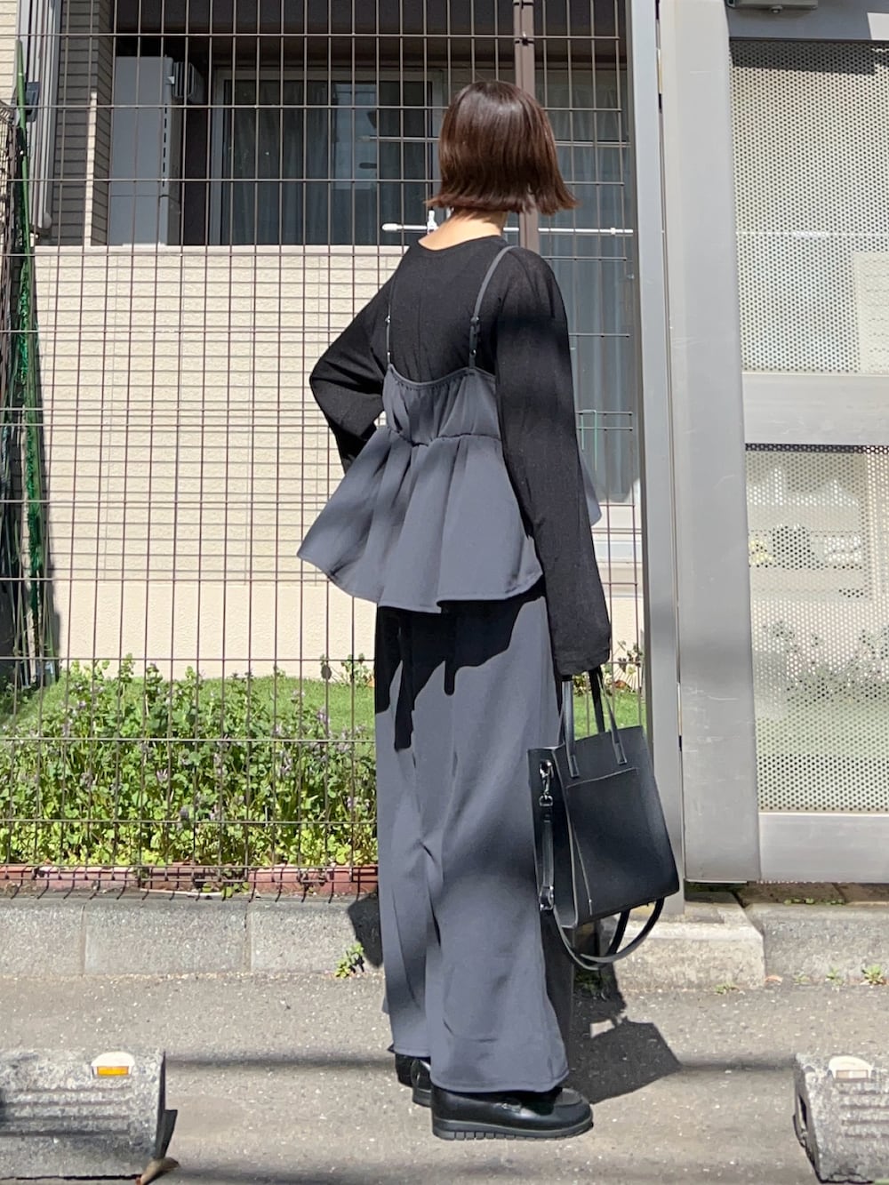 グレー系のワンピース、ブラック系のTシャツ/カットソー、ブラック系のショルダーバッグを着用したレディースの春コーディネートの2枚目の写真