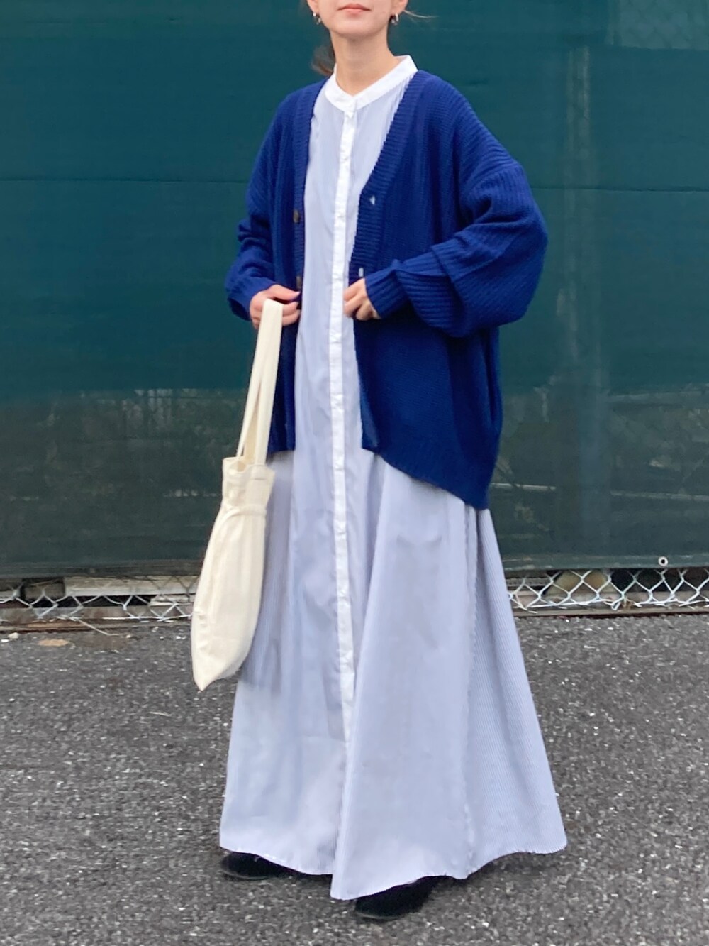 ブルー系のカーディガン/ボレロ、ブラック系のワンピース、ホワイト系のトートバッグを着用したレディースの秋コーディネートの2枚目の写真