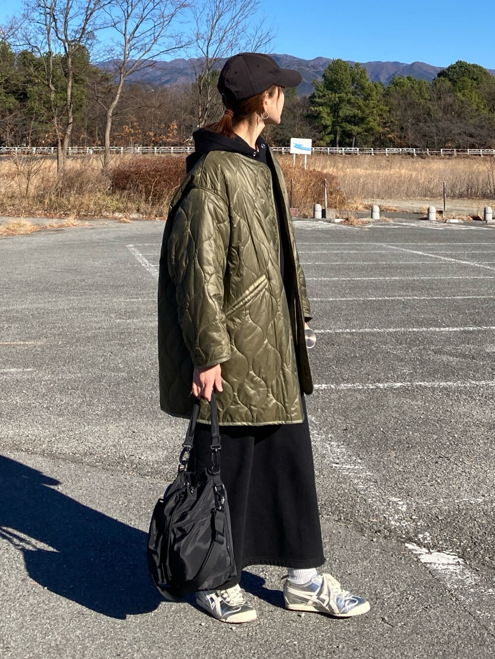 ブラック系のワンピース、ブラック系のショルダーバッグ、グリーン系のノーカラージャケットを着用したレディースの冬コーディネートの3枚目の写真