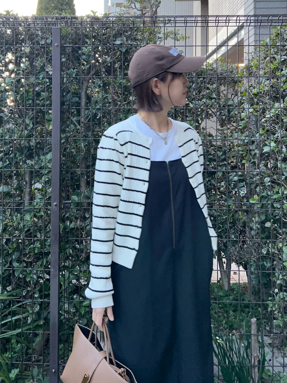 ブラウン系のハンドバッグ、ブラック系のワンピース、ホワイト系のカーディガン/ボレロを着用したレディースの冬コーディネートの2枚目の写真