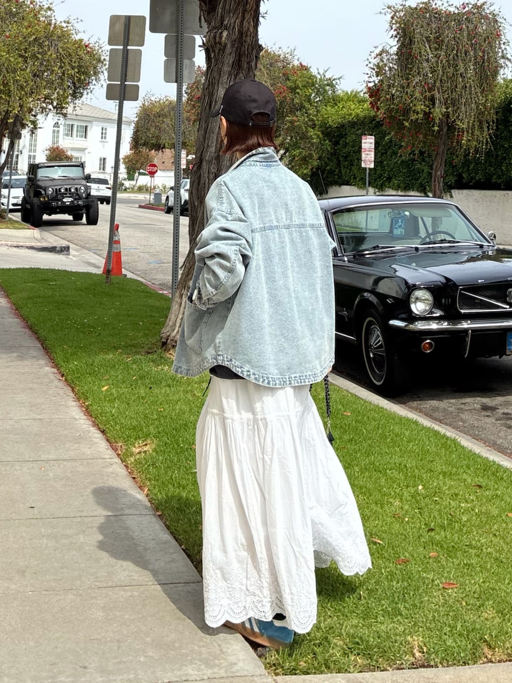 ブルー系のデニムジャケット、シルバー系のトートバッグ、ホワイト系のスカートを着用したレディースの春コーディネートの3枚目の写真