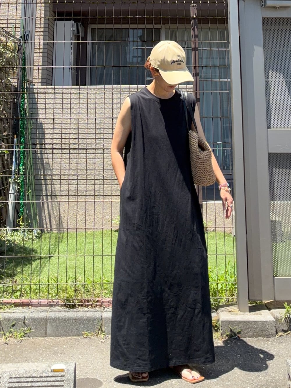 ブラック系のワンピース、イエロー系のトートバッグ、ベージュ系のキャップを着用したレディースの夏コーディネートの3枚目の写真