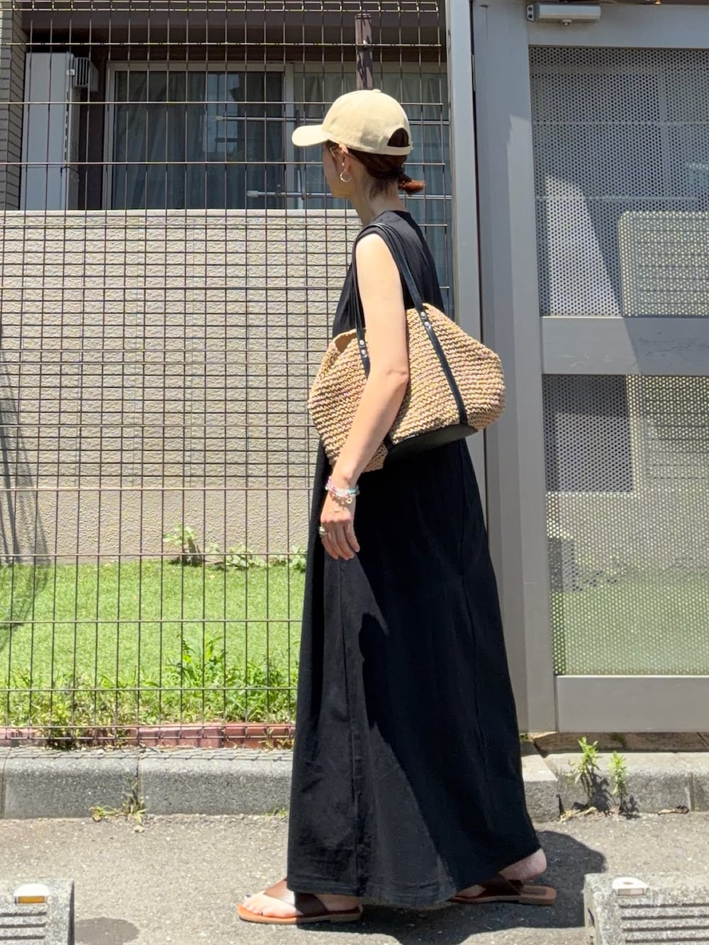 ブラック系のワンピース、イエロー系のトートバッグ、ベージュ系のキャップを着用したレディースの夏コーディネートの2枚目の写真
