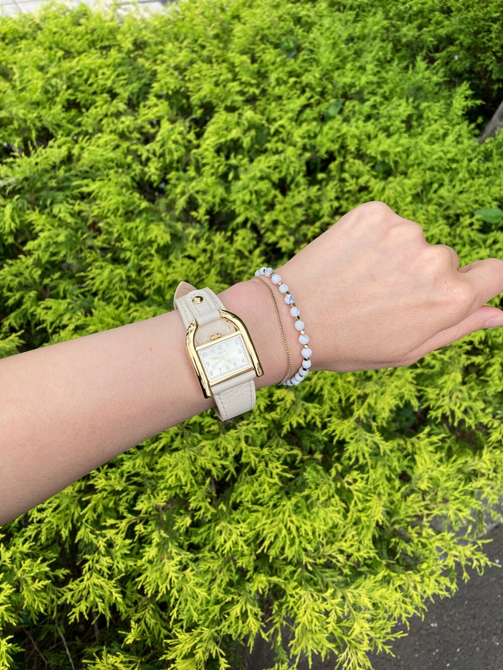 ホワイト系のスカート、グリーン系のショルダーバッグ、ブラウン系のアナログ腕時計を着用したレディースの夏コーディネートの3枚目の写真