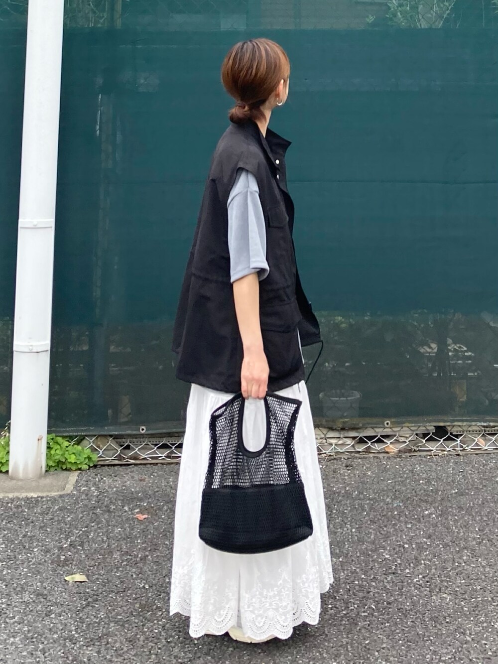 ブラック系のベスト、グレー系のTシャツ/カットソー、ホワイト系のスカートを着用したレディースの夏コーディネートの3枚目の写真