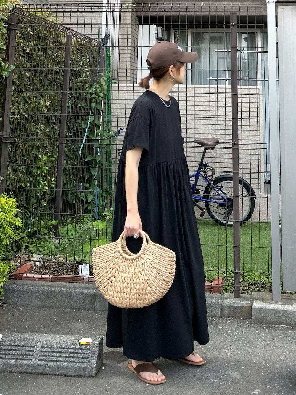 ブラック系のワンピース、ベージュ系のかごバッグ、シルバー系のリングを着用したレディースの夏コーディネートの2枚目の写真