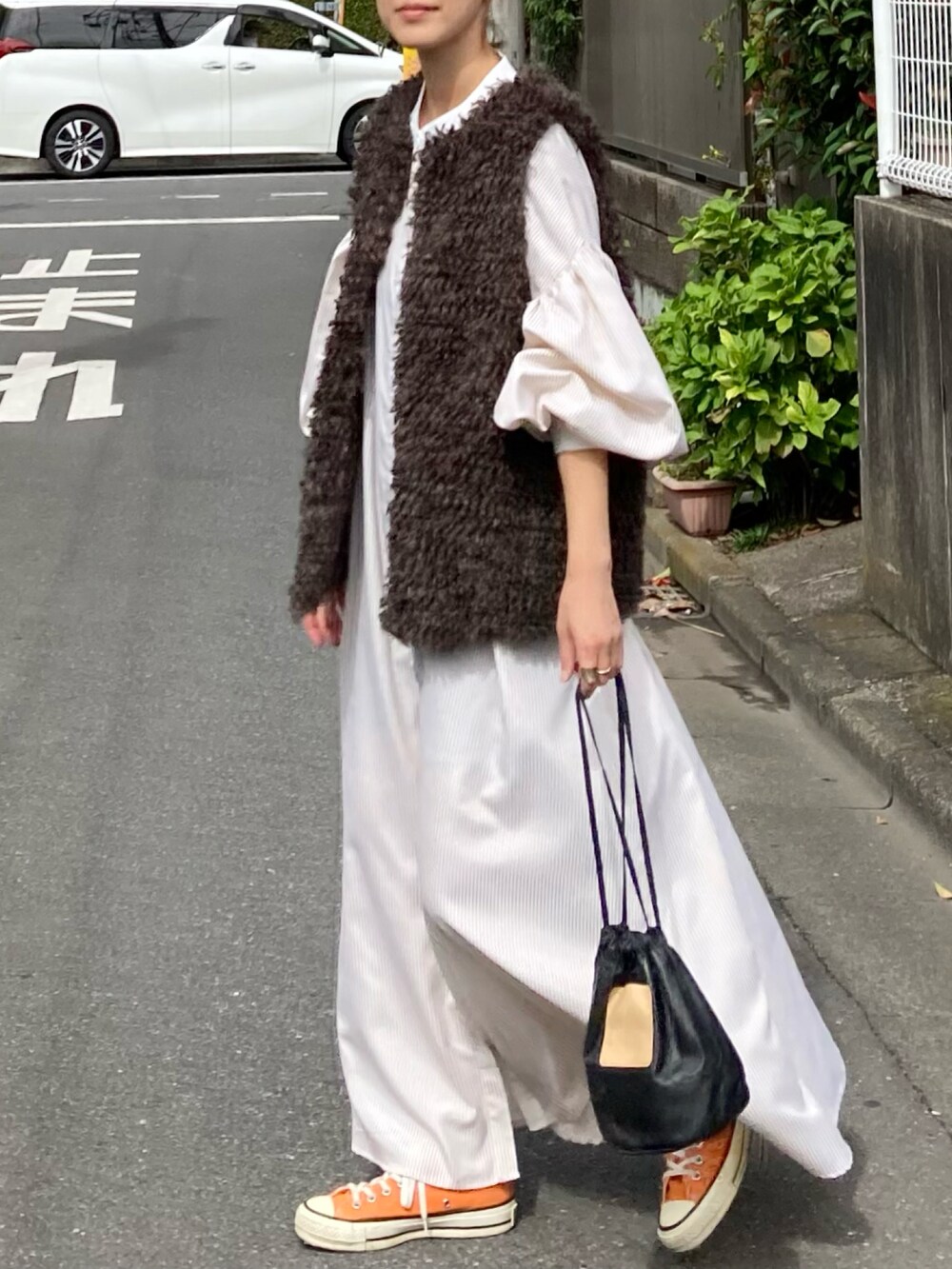 ブラウン系のベスト、ベージュ系のワンピース、ブラック系のハンドバッグを着用したレディースの秋コーディネートの2枚目の写真