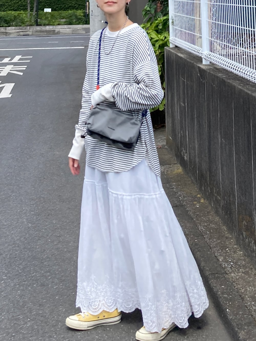 ブラック系のダウンベスト、ベージュ系のTシャツ/カットソー、ホワイト系のスカートを着用したレディースの秋コーディネートの4枚目の写真