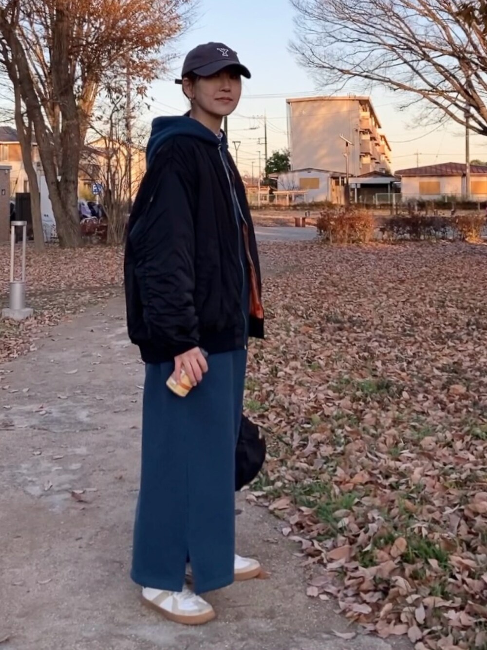 ブラック系のブルゾン、ブルー系のワンピース、ブラック系のショルダーバッグを着用したレディースの冬コーディネートの4枚目の写真