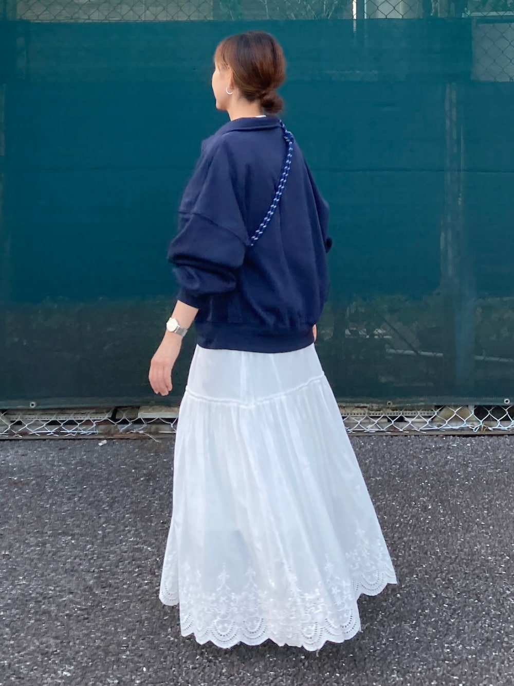 ブルー系のスウェット、ホワイト系のスカート、グレー系のショルダーバッグを着用したレディースの秋コーディネートの4枚目の写真