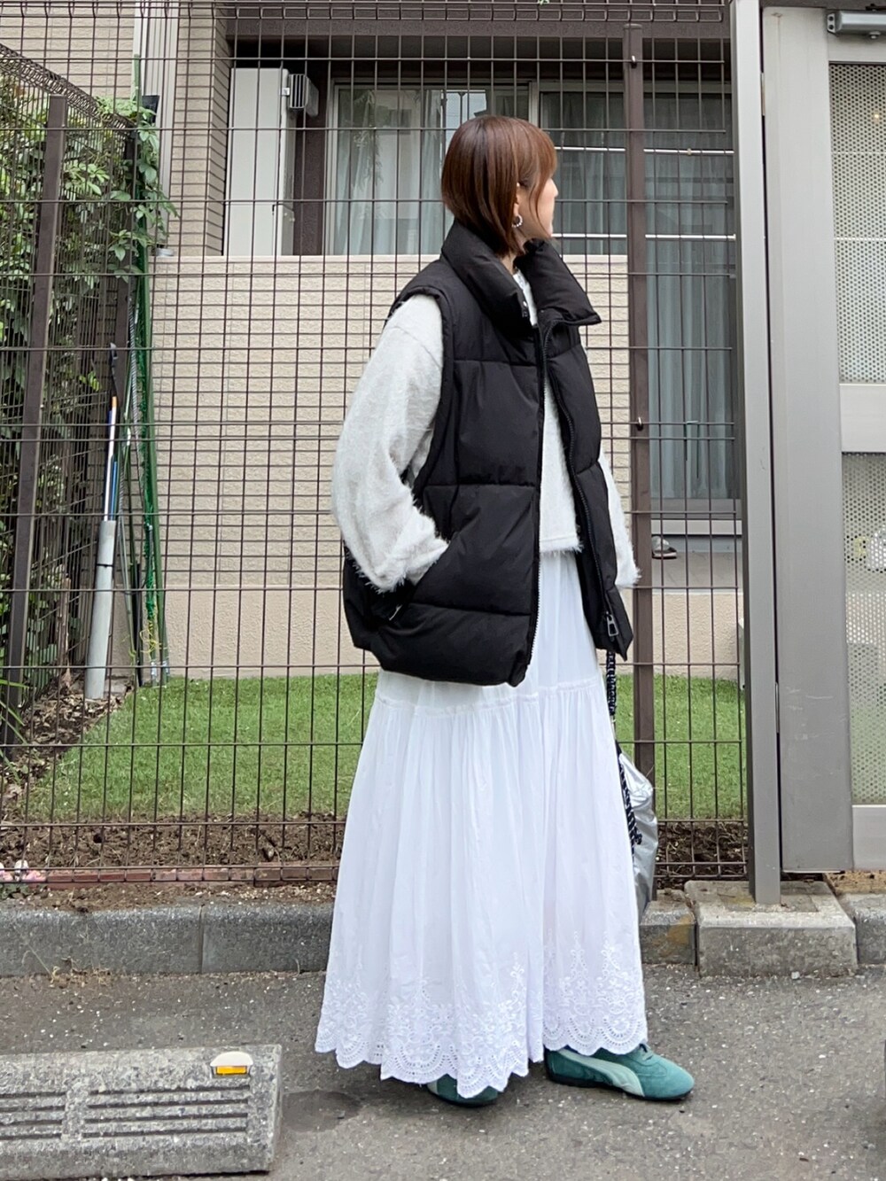 グレー系のニット/セーター、ホワイト系のスカート、シルバー系のショルダーバッグを着用したレディースの秋コーディネートの2枚目の写真