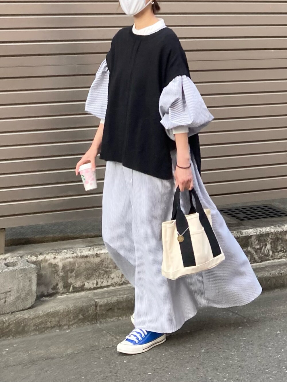 ブラック系のワンピース、ブラック系のベスト、ホワイト系のトートバッグを着用したレディースの春コーディネートの2枚目の写真