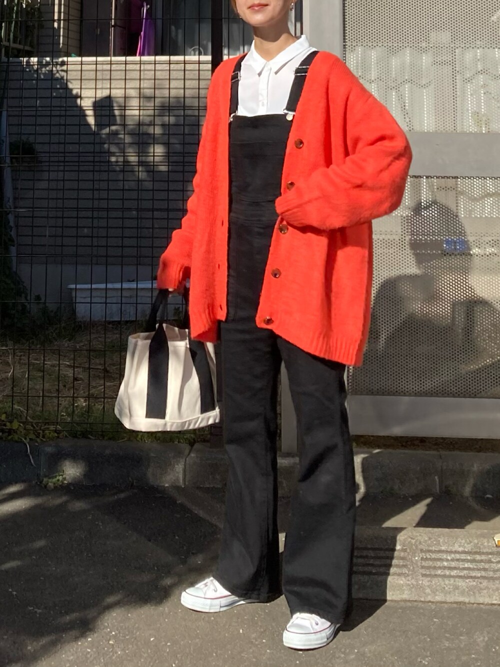 オレンジ系のカーディガン/ボレロ、ホワイト系のシャツ/ブラウス、ブラック系のサロペット/オーバーオールを着用したレディースの冬コーディネートの3枚目の写真