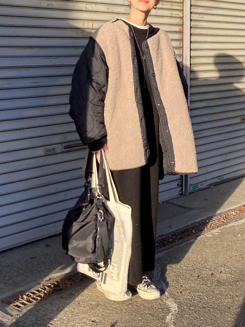 ブラック系のブルゾン、ブラック系のショルダーバッグ、ブラック系のワンピースを着用したレディースの冬コーディネートの3枚目の写真