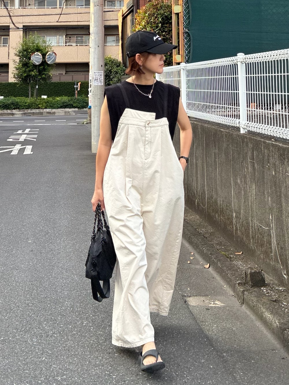 ホワイト系のサロペット/オーバーオール、ブラック系のTシャツ/カットソー、ブラック系のトートバッグを着用したレディースの夏コーディネートの5枚目の写真