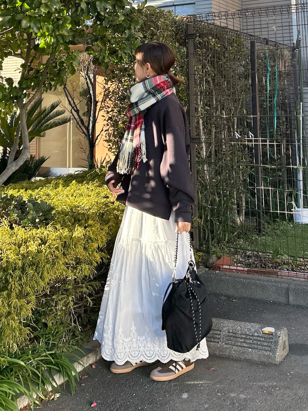 グレー系のTシャツ/カットソー、ホワイト系のスカート、ブラック系のトートバッグを着用したレディースの冬コーディネートの4枚目の写真