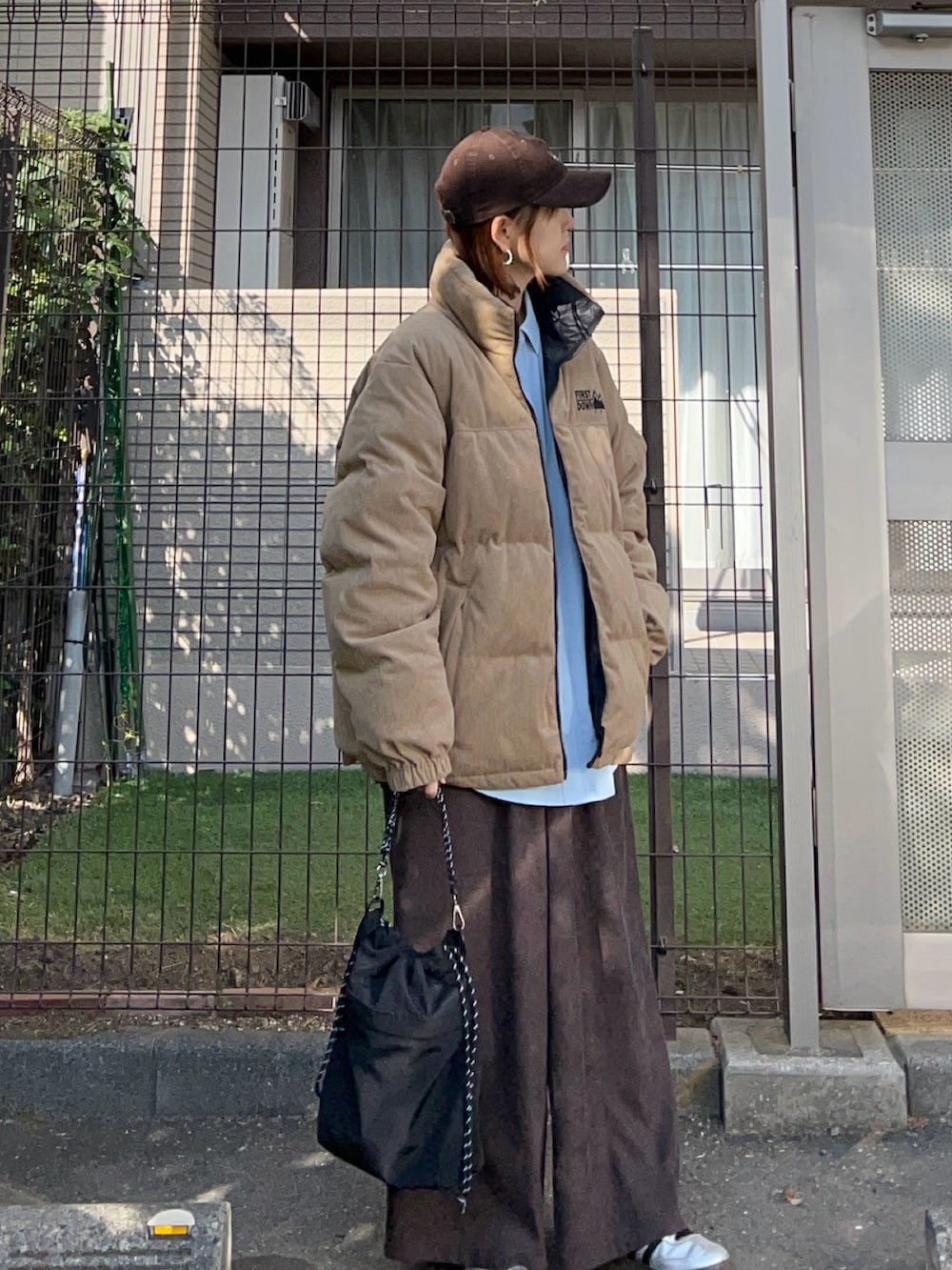 ベージュ系のダウンジャケット/コート、ブラウン系のスラックス、ブラック系のトートバッグを着用したレディースの冬コーディネートの2枚目の写真