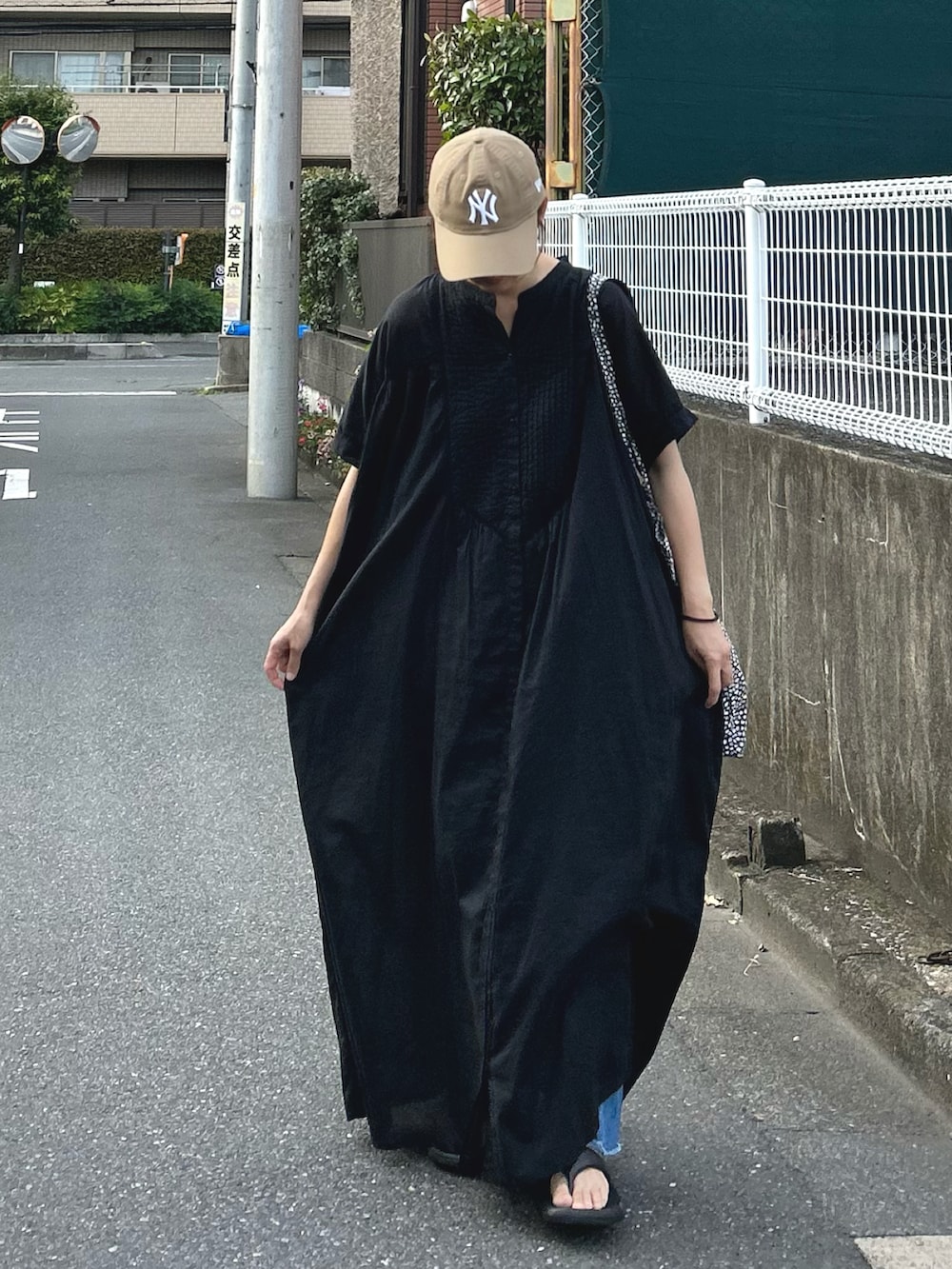 ブルー系のデニムパンツ、ブラック系のワンピース、ベージュ系のキャップを着用したレディースの夏コーディネートの2枚目の写真