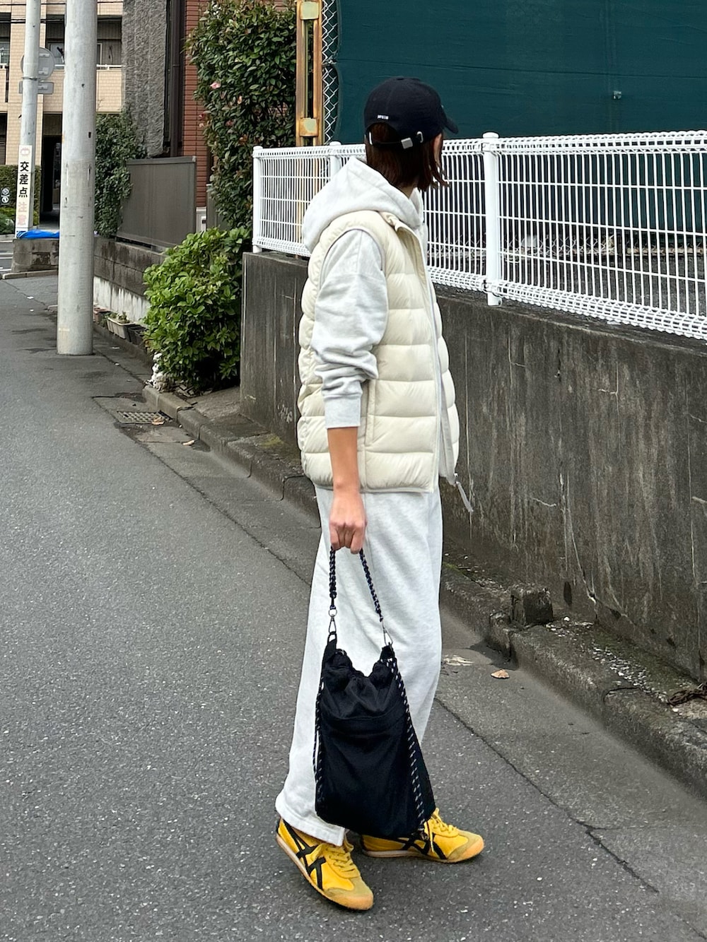 ホワイト系のダウンベスト、ブラック系のショルダーバッグ、グレー系のワンピースを着用したレディースの秋コーディネートの4枚目の写真