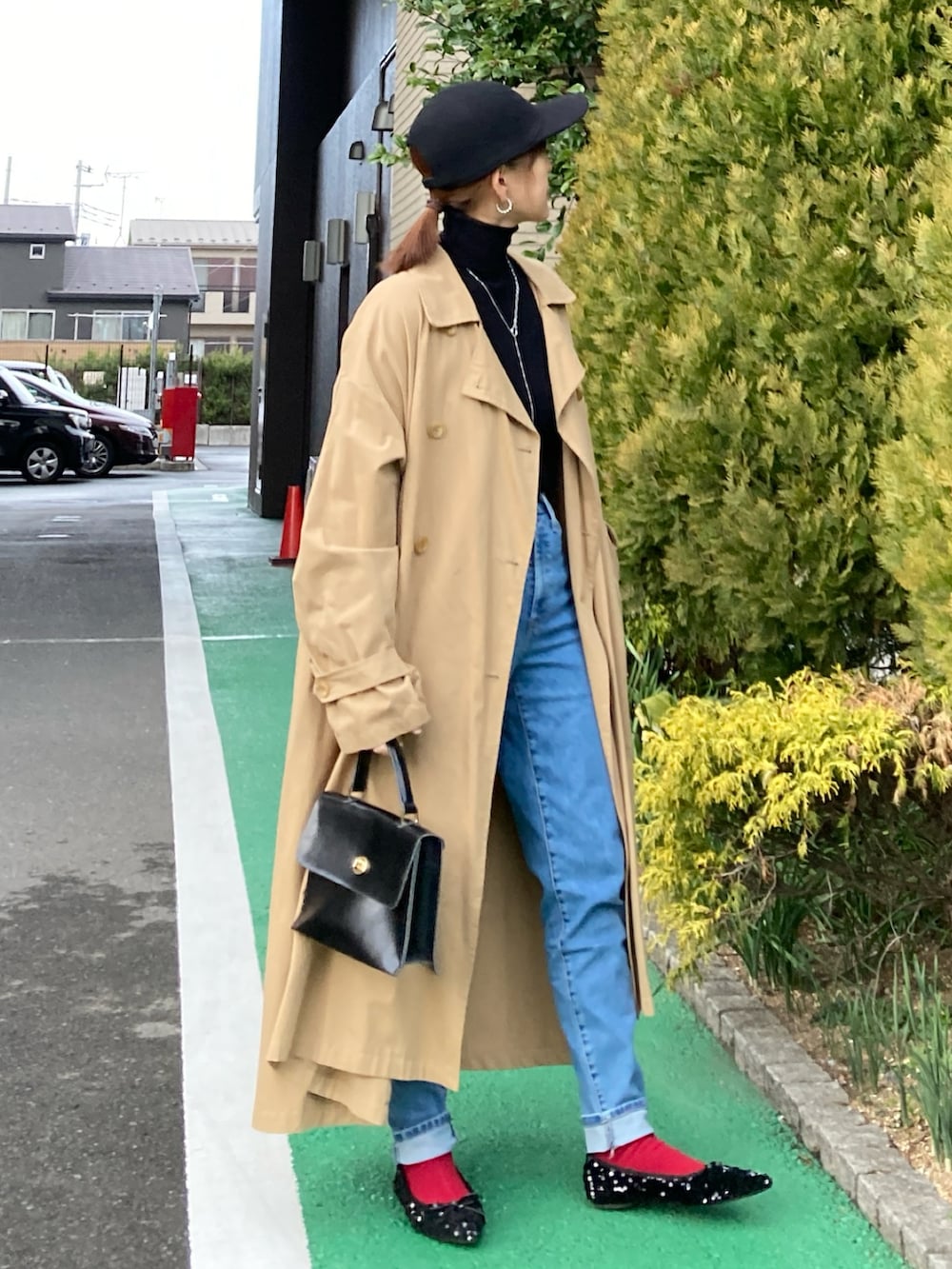 ブラック系のニット/セーター、ブルー系のデニムパンツ、ベージュ系のチェスターコートを着用したレディースの冬コーディネートの2枚目の写真