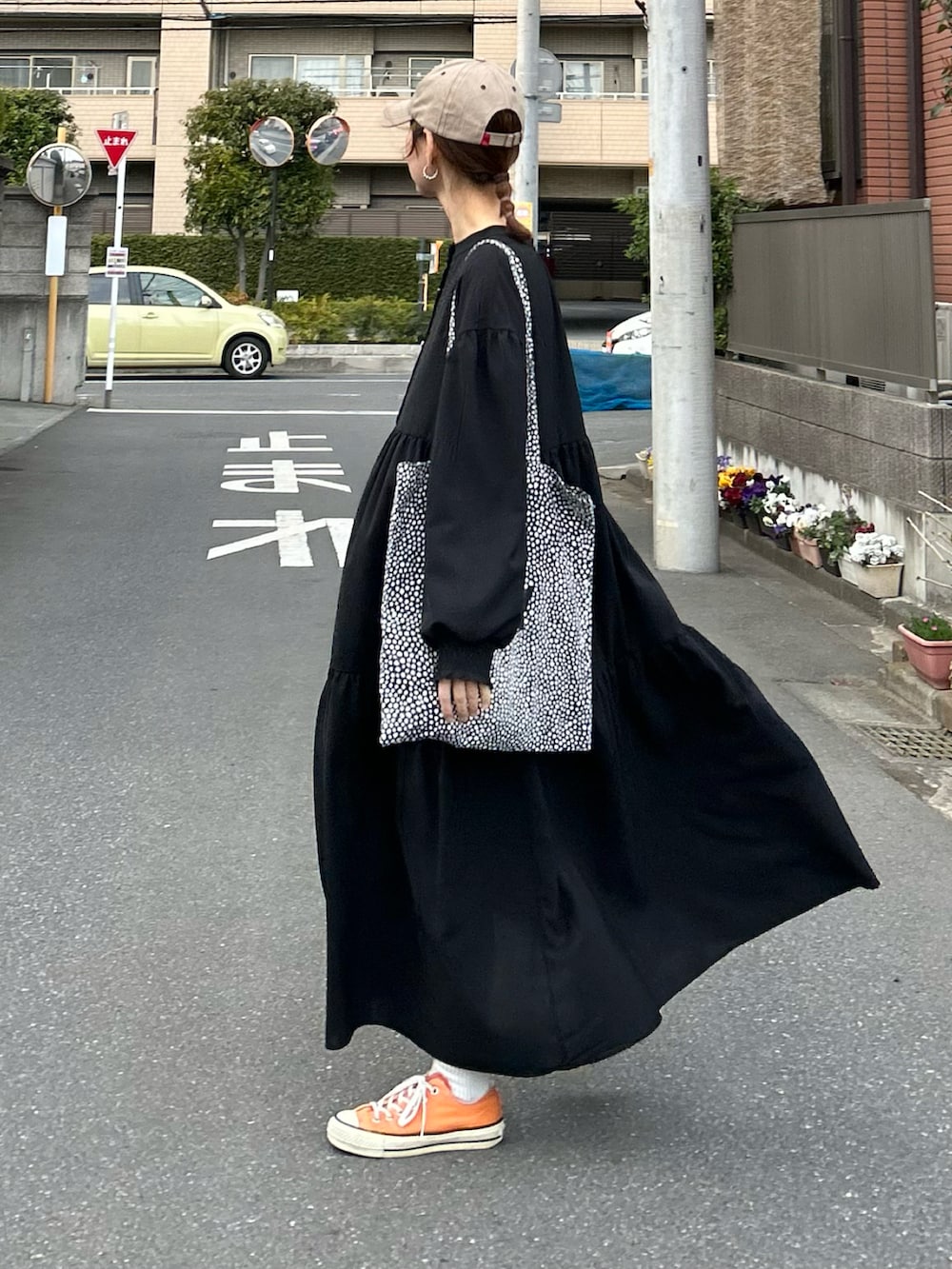 ブラック系のシャツワンピース、ブラック系のトートバッグ、ベージュ系のキャップを着用したレディースの春コーディネートの2枚目の写真