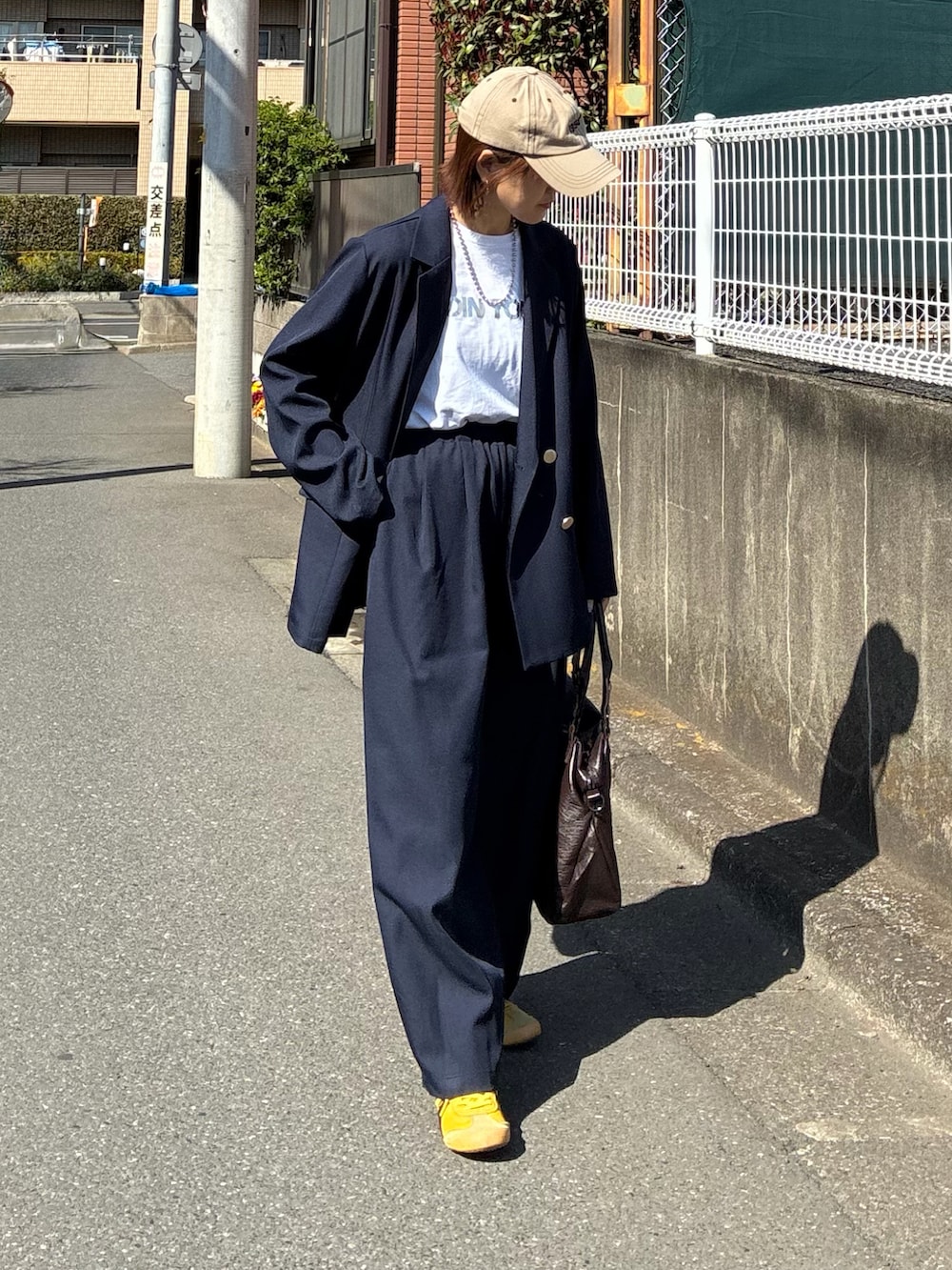 ブルー系のテーラードジャケット、ブルー系のスラックス、ブラウン系のトートバッグを着用したレディースの春コーディネートの5枚目の写真