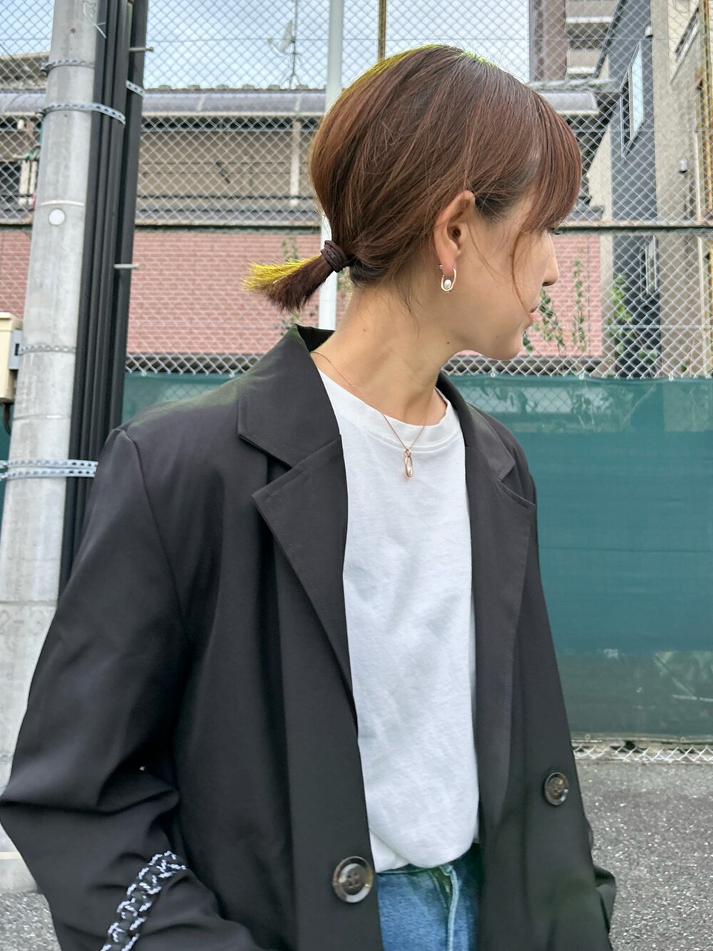 ブラック系のテーラードジャケット、ブルー系のデニムパンツ、グリーン系のトートバッグを着用したレディースの秋コーディネートの2枚目の写真