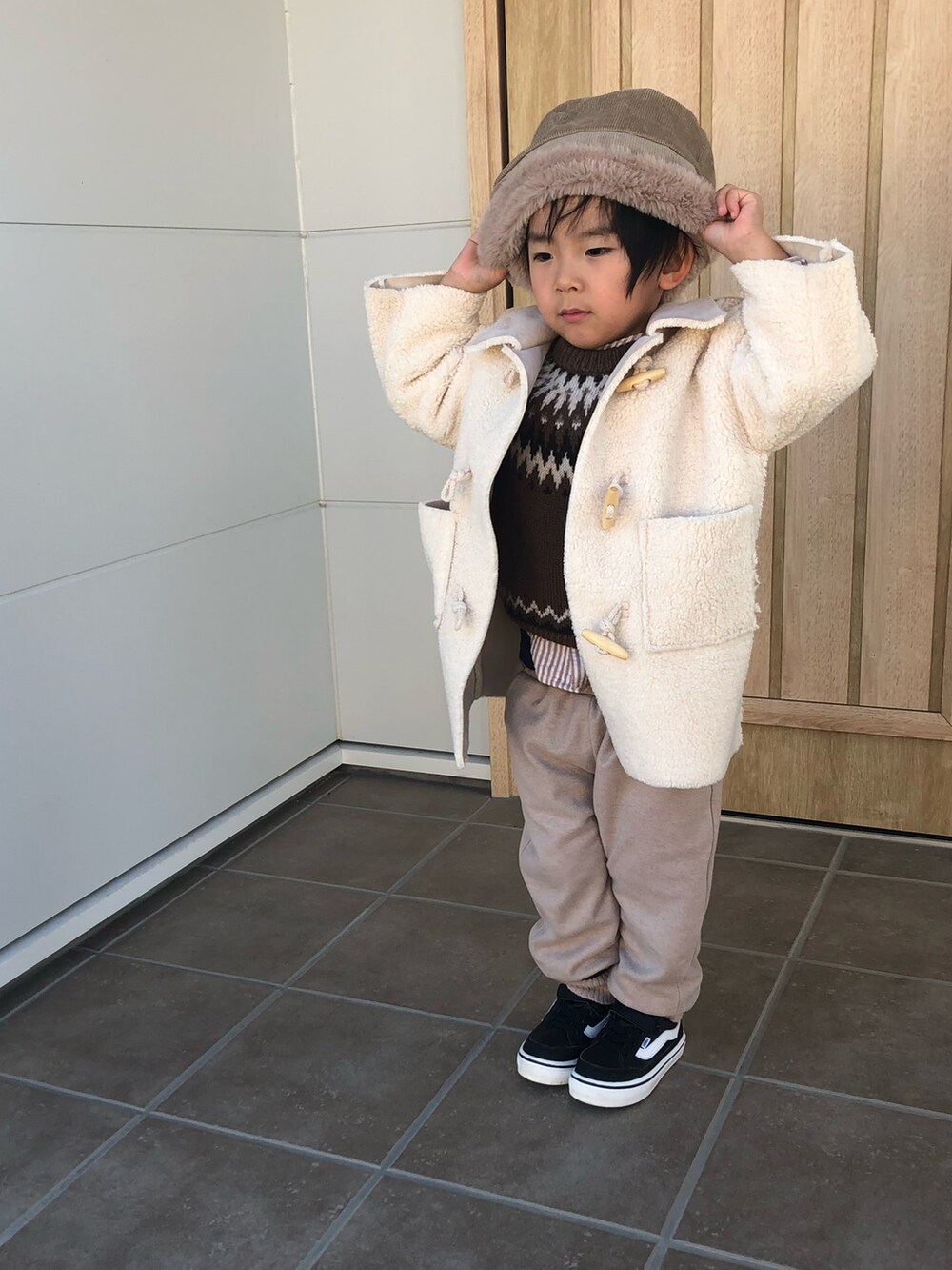 ブラック系のスニーカー、ホワイト系のジャケット/アウター、ベージュ系のパンツを着用したキッズの冬コーディネートの3枚目の写真