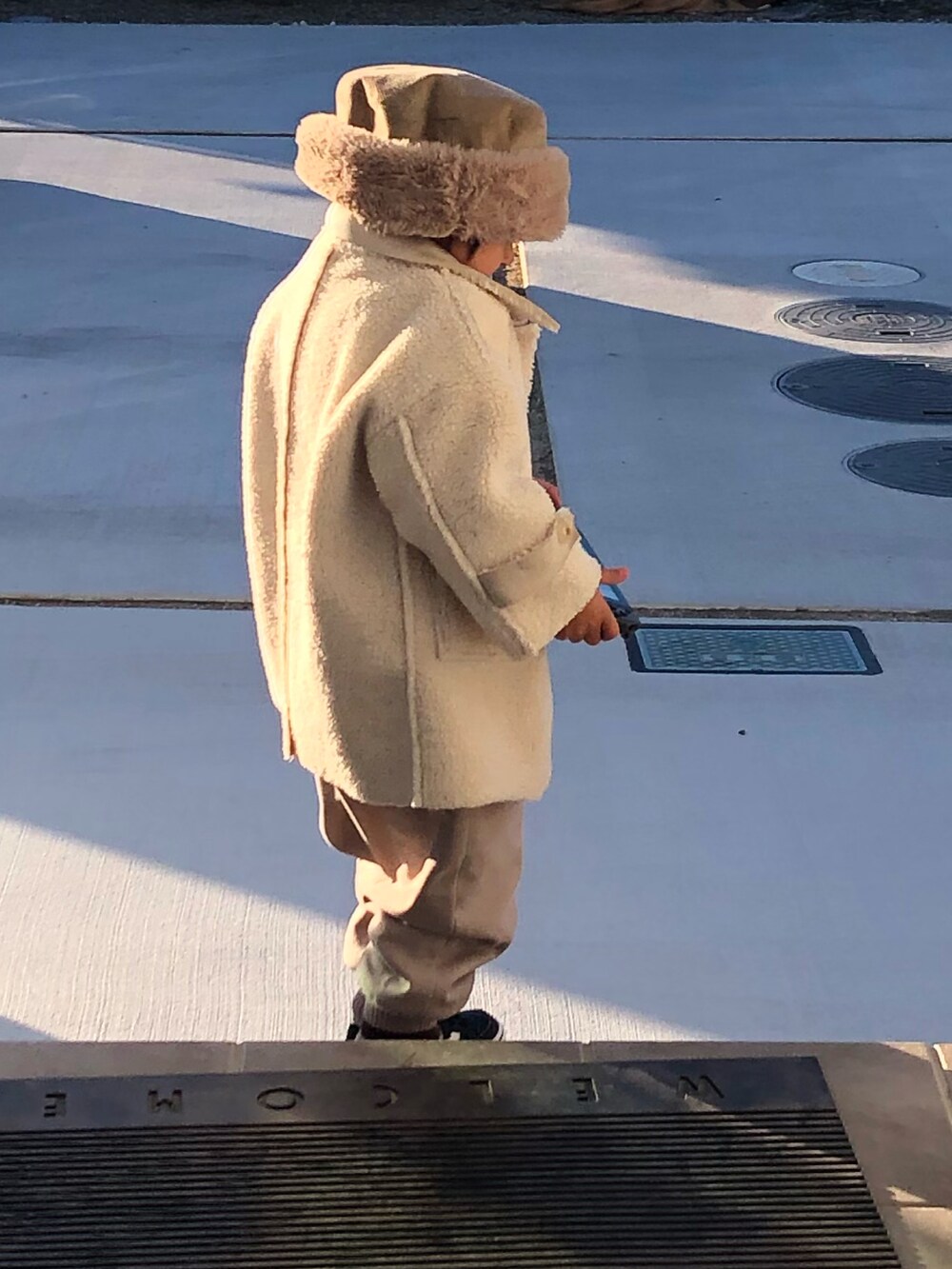 ブラック系のスニーカー、ホワイト系のジャケット/アウター、ベージュ系のパンツを着用したキッズの冬コーディネートの2枚目の写真