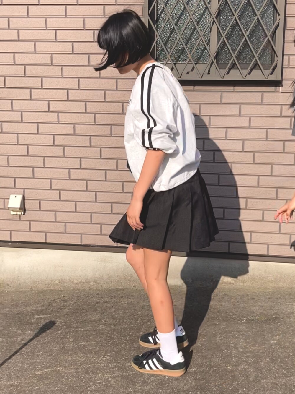 グレー系のTシャツ/カットソー、ブラック系のスカート、ブラック系のスニーカーを着用したキッズの春コーディネートの2枚目の写真